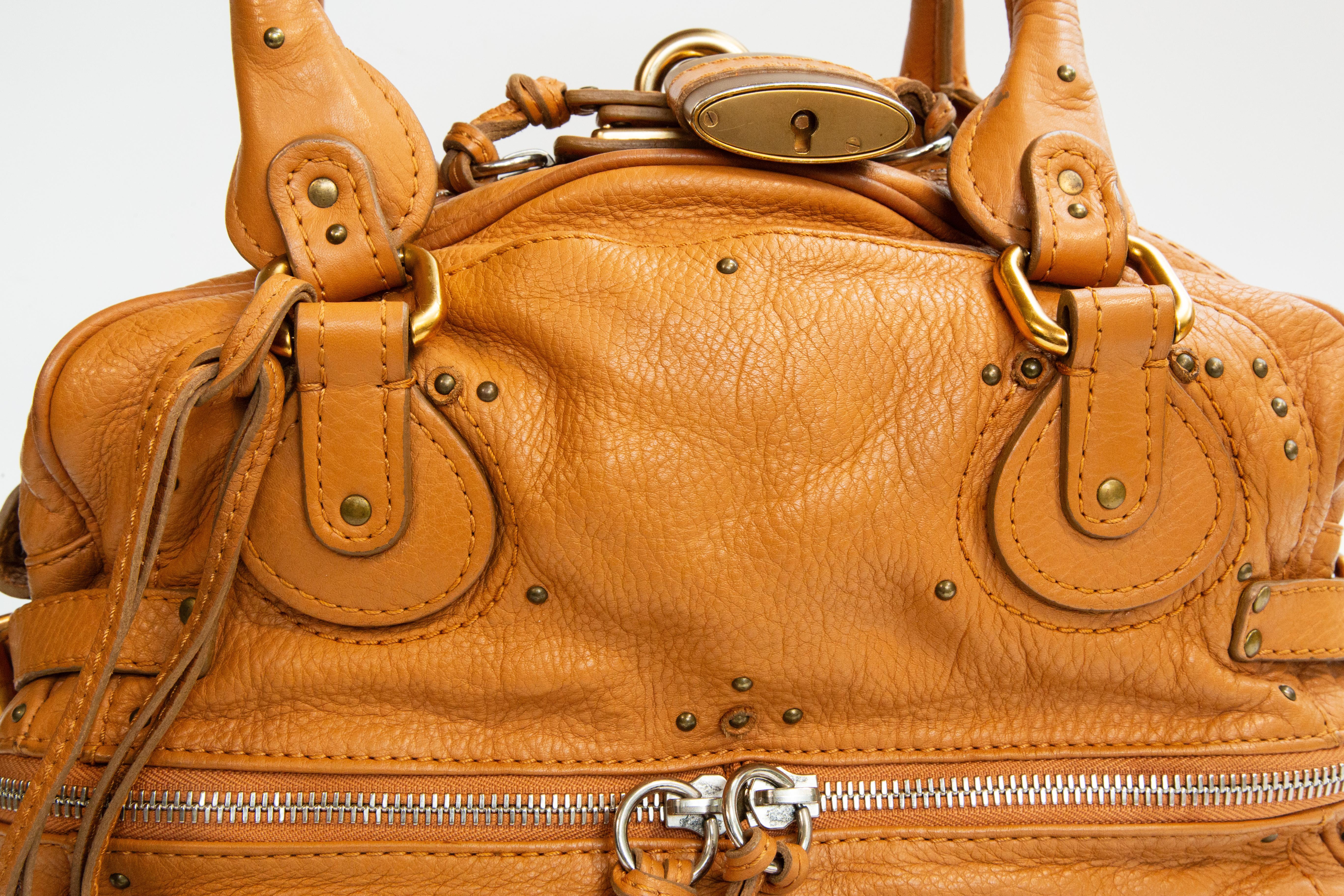 Chloe Paddington top handle /shoulder bag made of light brown leather with gold toned hardware. The interior is lined with light beige canvas, and next to the major compartment it features two side pockets of which one has a zipper. In addition, the