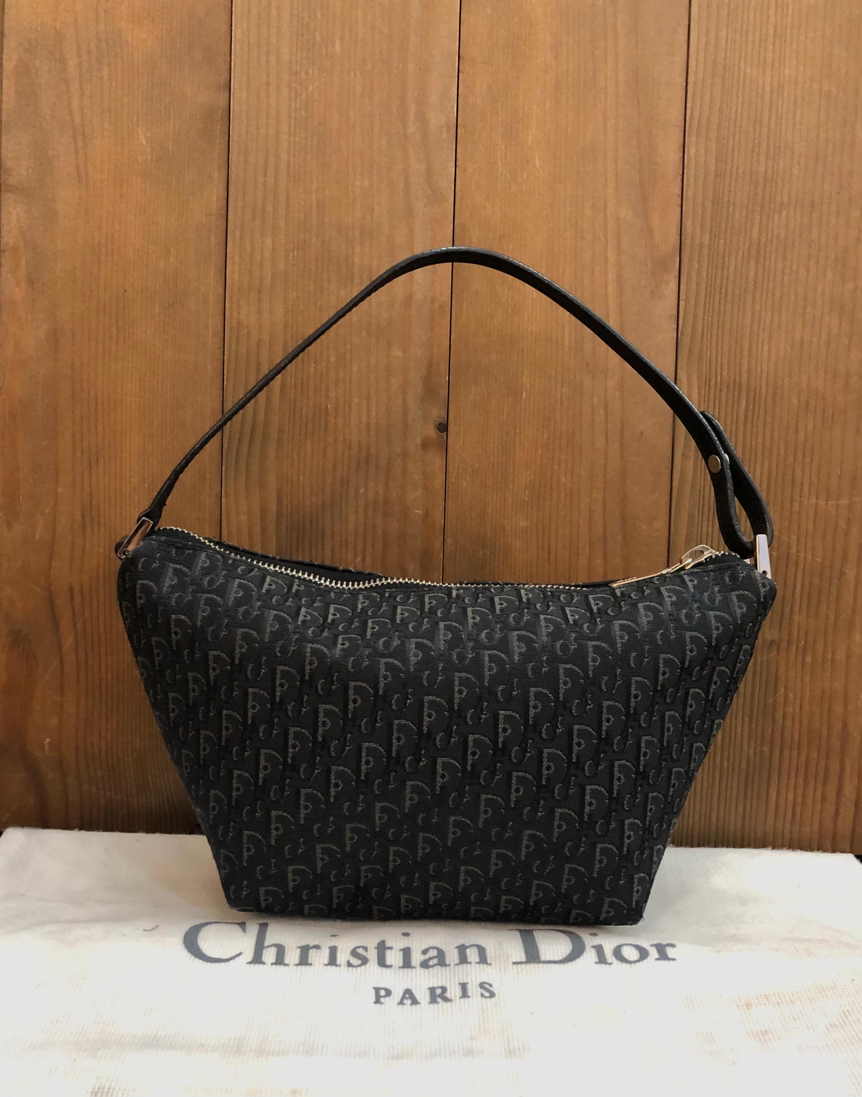 This vintage Christian Dior pouch handbag is crafted of Dior’s micro trotter jacquard and leather in black featuring silver toned hardware. Top zipper closure opens an unlined coated interior. Made in Spain MC 0063. Measures approximately 9 (top) 5