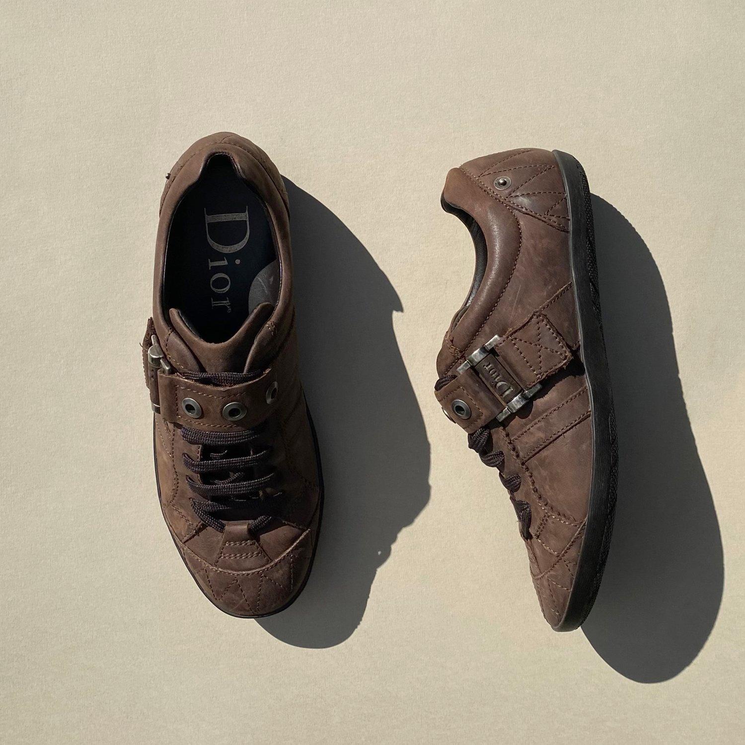 Vintage brown leather trainers by Dior from the early 2000’s. John Galliano era. In a brown leather finish, with lace up and pull over fastenings. Featuring the brands classic Dior logo in silver hardware to the fastenings and logo engraved into the