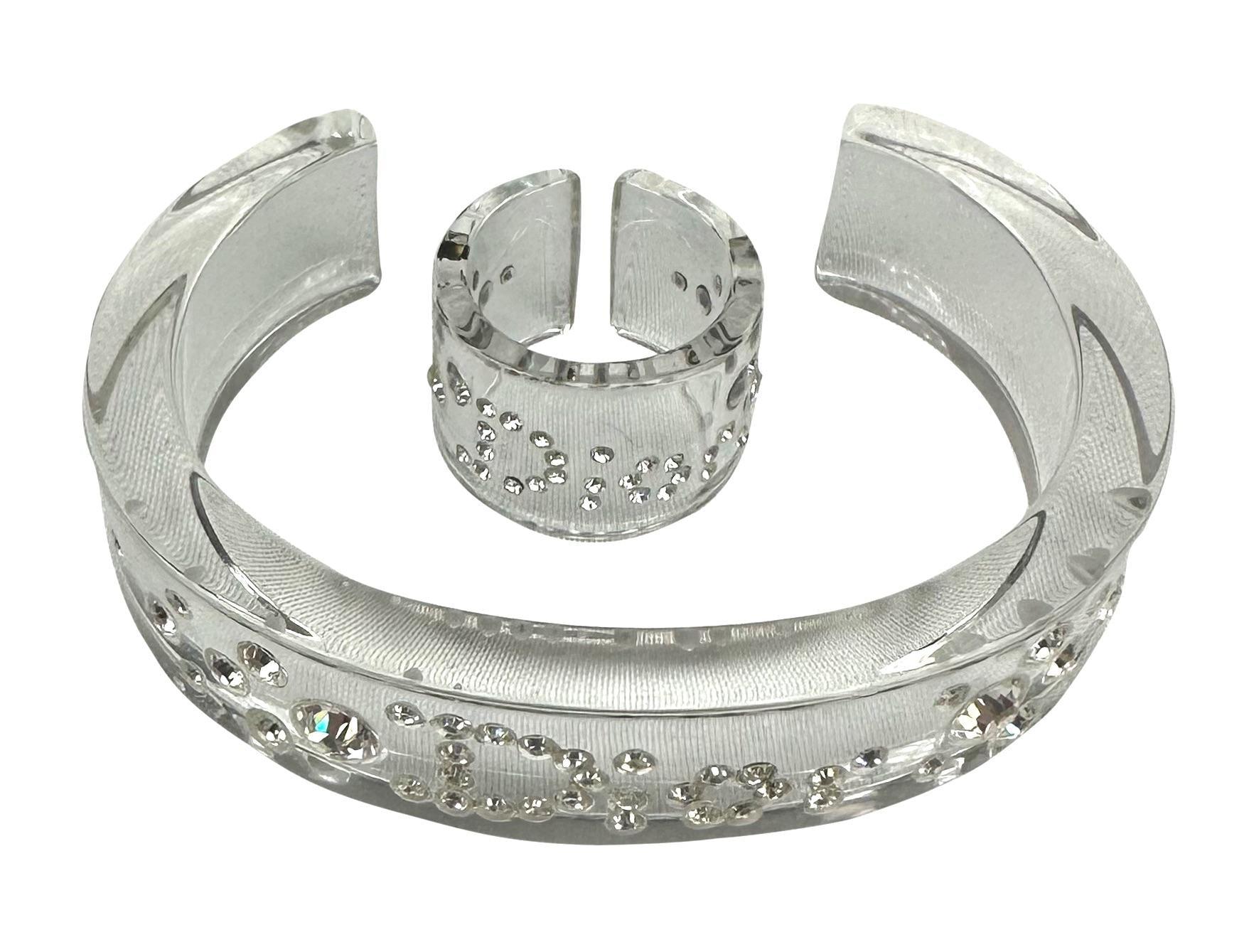 Presentamos un conjunto de brazalete y anillo Christian Dior de cristal transparente diseñado por John Galliano. Desde principios de la década de 2000, este conjunto de lucita ha sido el complemento perfecto del efecto 2000 para cualquier atuendo.