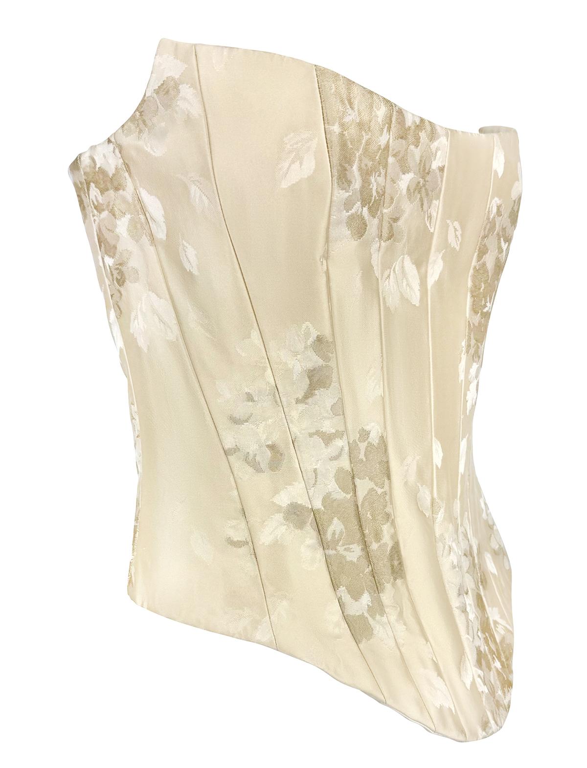 From the 2000s, this Christian Lacroix bridal corset top is crafted from off-white floral satin jacquard. The strapless silhouette features structured vertical paneling and internal boning for sculpted support, finished with a concealed zip at the