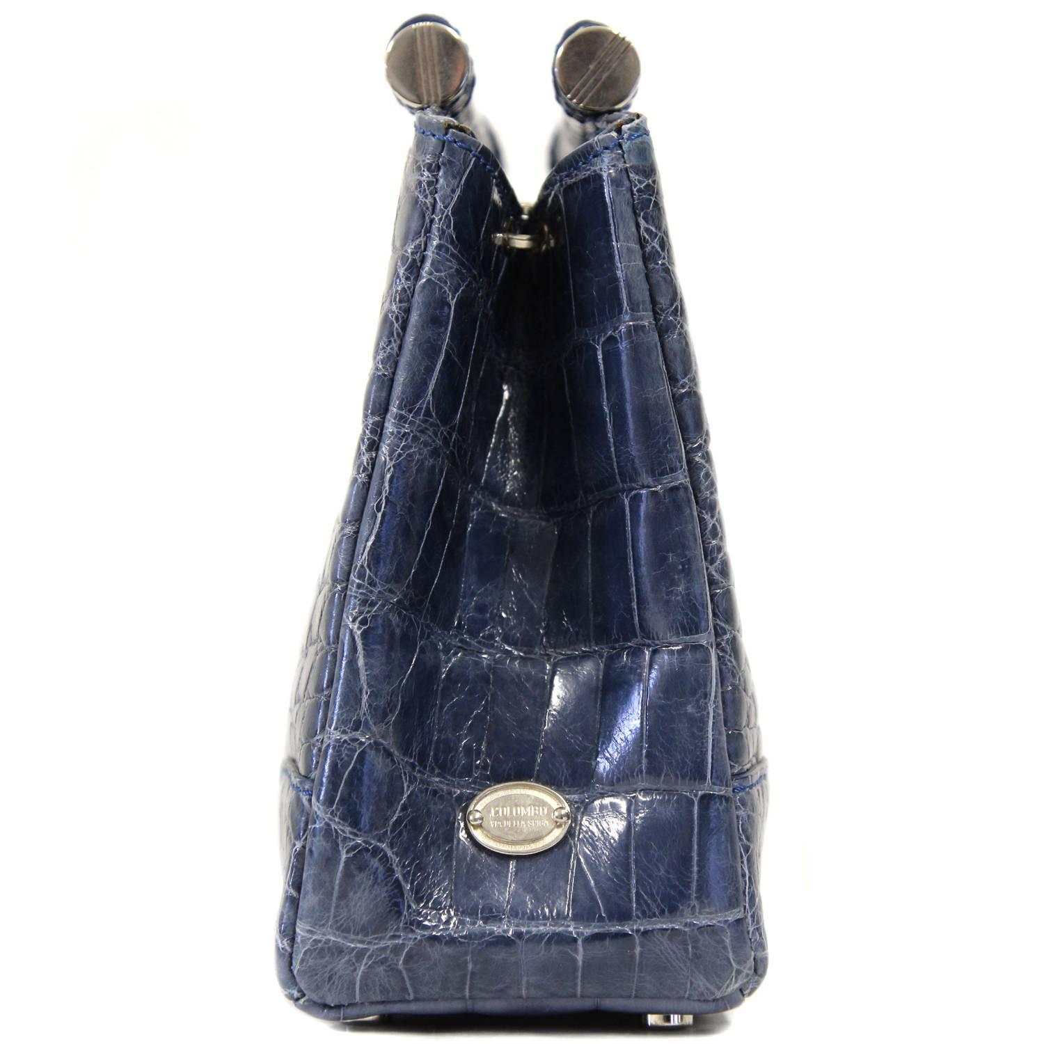 Pretty crocodile leather handbag in blue-gray color made by Colombo Via della Spiga with silver hardware. The bag features two coated iron handles, a press-button closure and an internal zipped pocket. Lined in suede. The item comes with a short