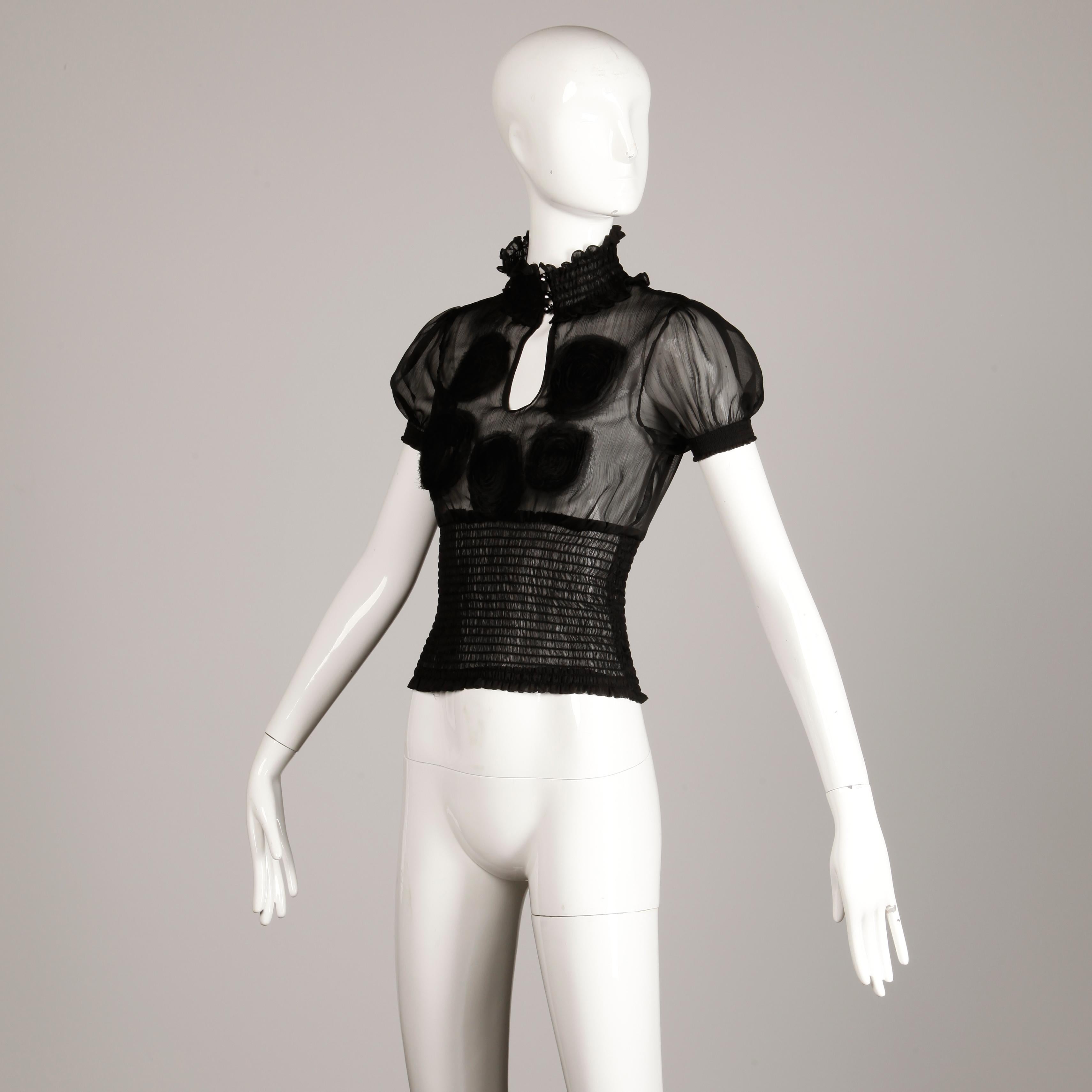 Costume National short sleeve sheer black top or blouse with rhinestone buttons and elastic smocking. Embroidered detail and keyhole front. Front button closure. Waistband, sleeve cuffs and neckline are stretchy. The marked size is 40 and this fits