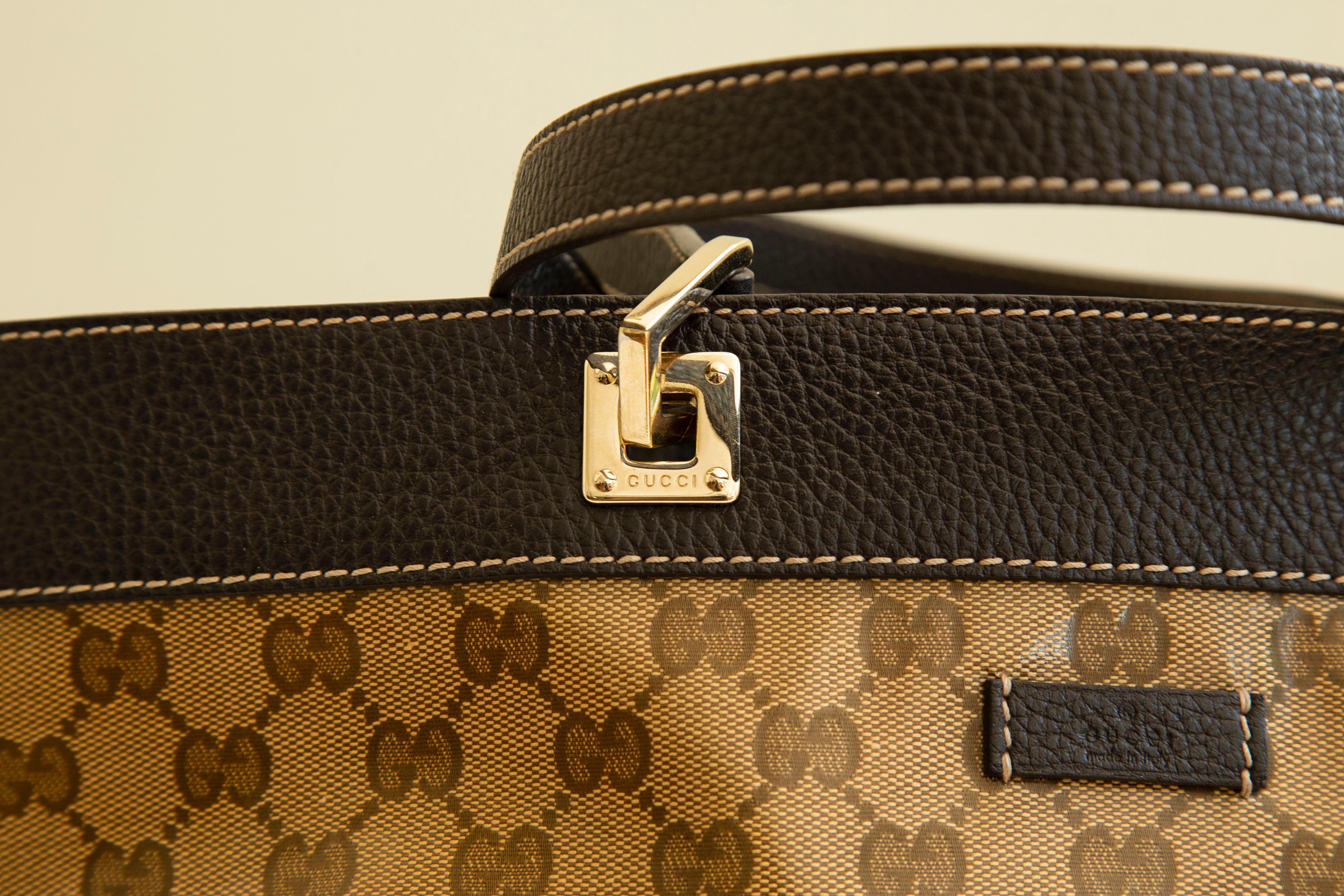 A GUCCI crystal monogram tote in brown. The bag is made of coated canvas  with brown leather trim and light gold toned hardware. The interior is lined with brown fabric, and next to the major compartment it has one zipped side pocket.
The exterior