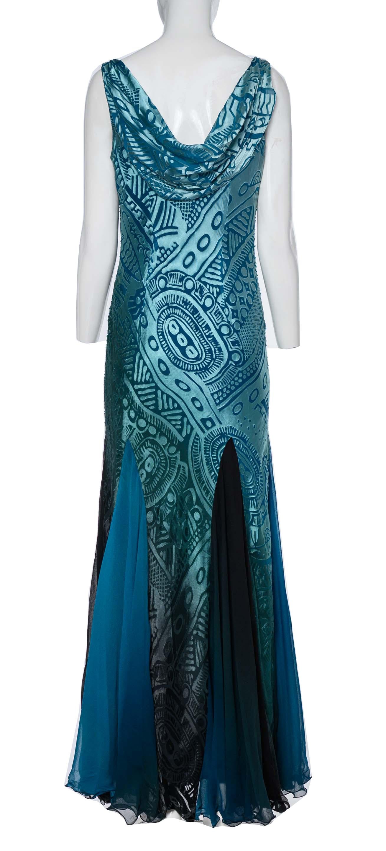 The Diane Freis Burnout Effect Sequinned Dress is a mesmerizing and glamorous piece. Designed with a cowl neck, it creates a beautifully draped collar and back, exuding an air of elegance and sophistication. The dress features a luxurious turquoise