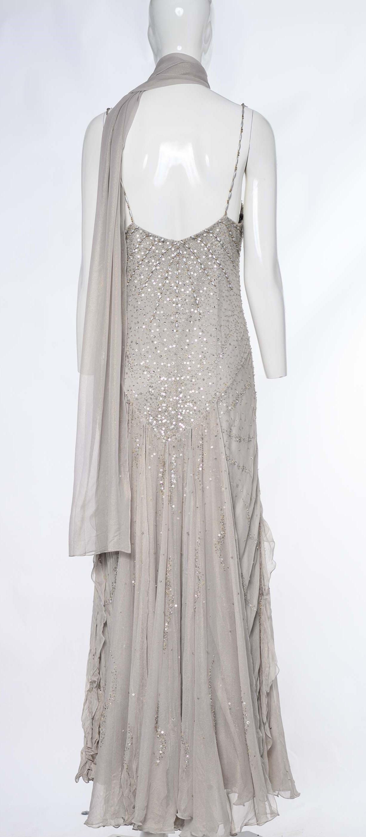 Crafted from soft silk fabric, this dress emanates elegance and sophistication. The light grey sheer fabric is enhanced with a subtle gold shimmer, adding a touch of opulence and creating a radiant effect.

The dress is adorned with tonal sequin and