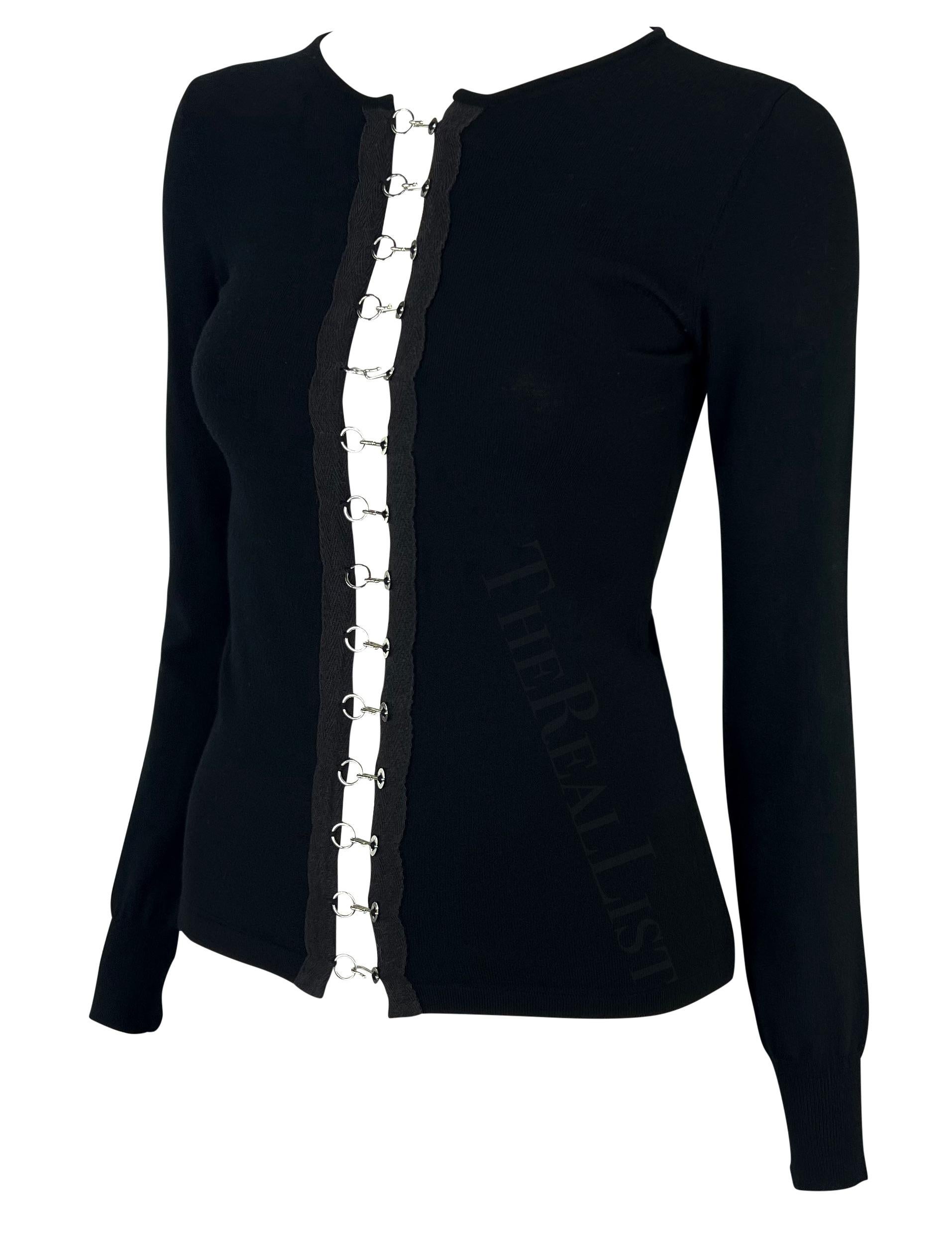 Presenting a fabulous black knit Dolce and Gabbana cardigan. From the early 2000s, this form-fitting cardigan is made complete with silver-tone hook closures that run down the front of the top. Add this edge and elevated closet staple to your