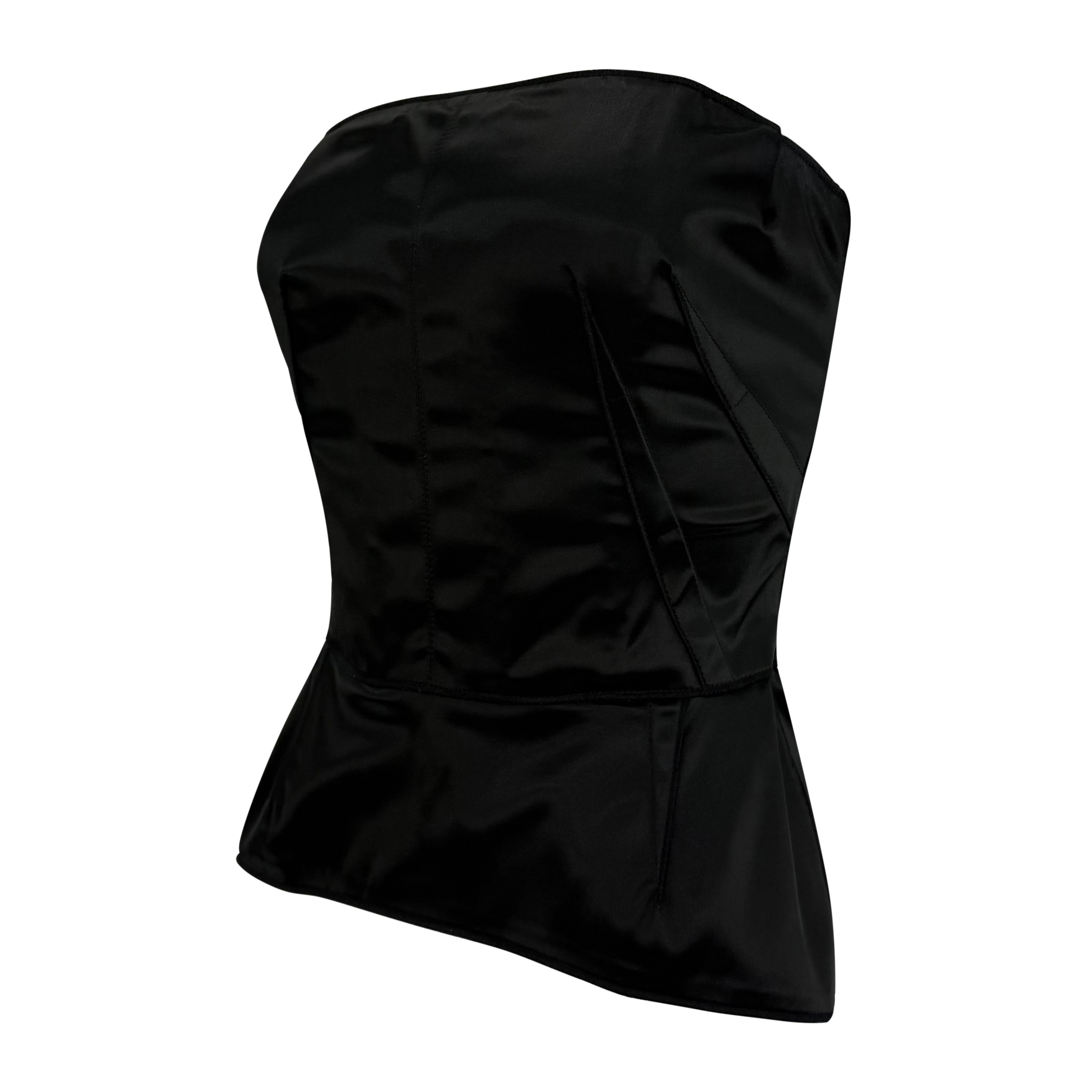 Datant des années 2000, ce top bustier en satin noir Dolce & Gabbana présente un désossage interne pour une silhouette sculptée. Le modèle est complété par un péplum subtil à l'ourlet et une fermeture à glissière dissimulée au dos. 

Mesures