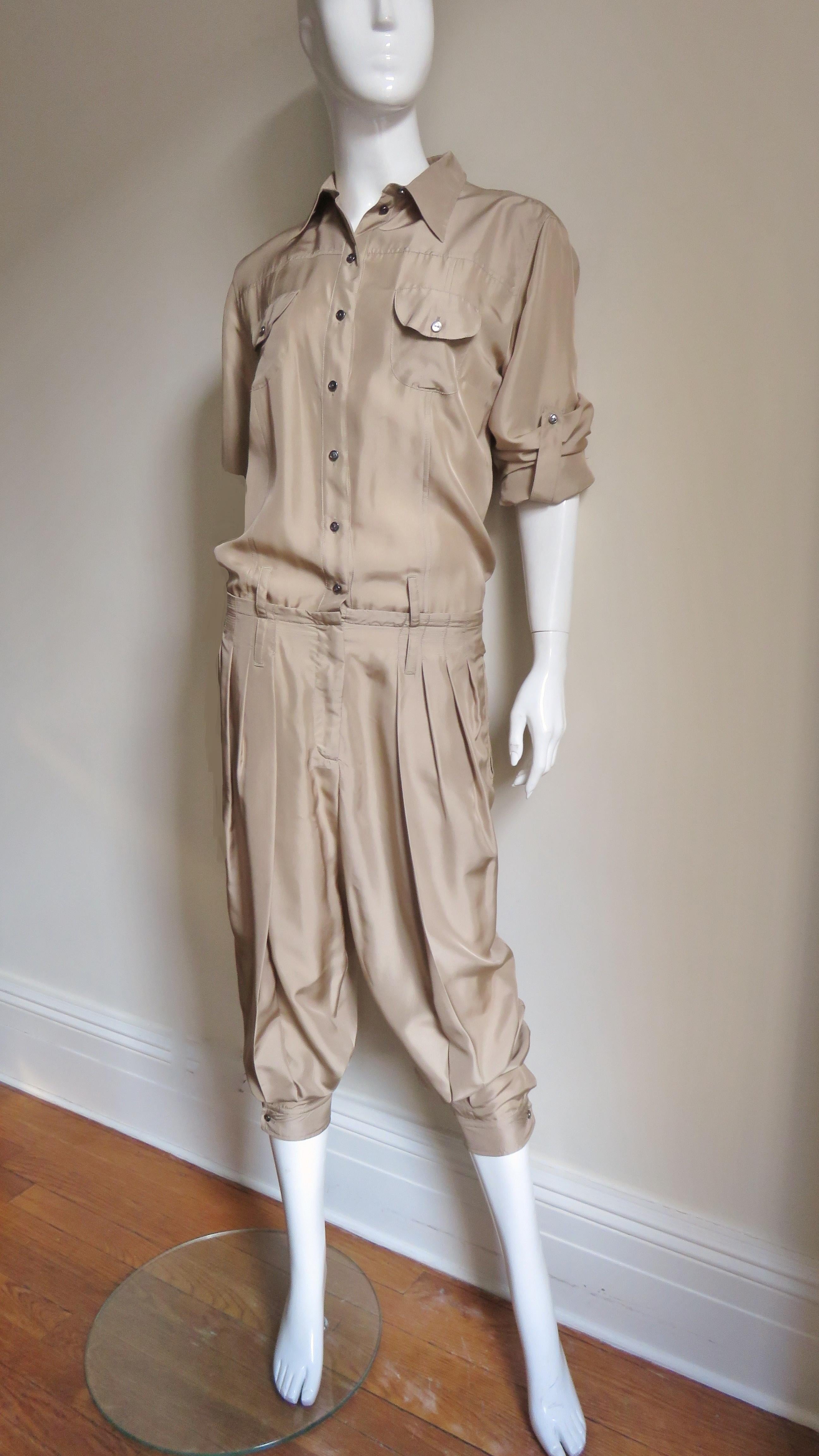 A fabulous khaki silk jumpsuit by Dolce & Gabbana.  It has a shirt collar, 2 breast pockets and a drop waistline.  The long sleeves have a 1 button cuff and the ability to be pulled up above the elbow and held in place with a button strap. The pants