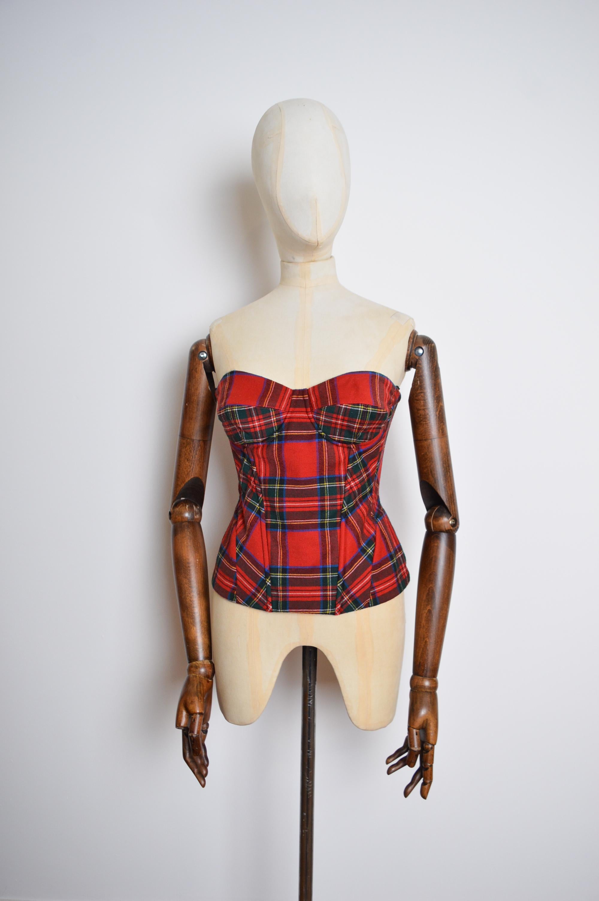 Fun early 2000's Dolce & Gabbana boned Corset crafted from a Red Tartan Wool material with a Black satin interior lining. 
 
Features;
Chrome Double Zip Back Closure
Hip shaped panelling
Boned body
Underwired
89% Virgin Wool
 
Sizing in