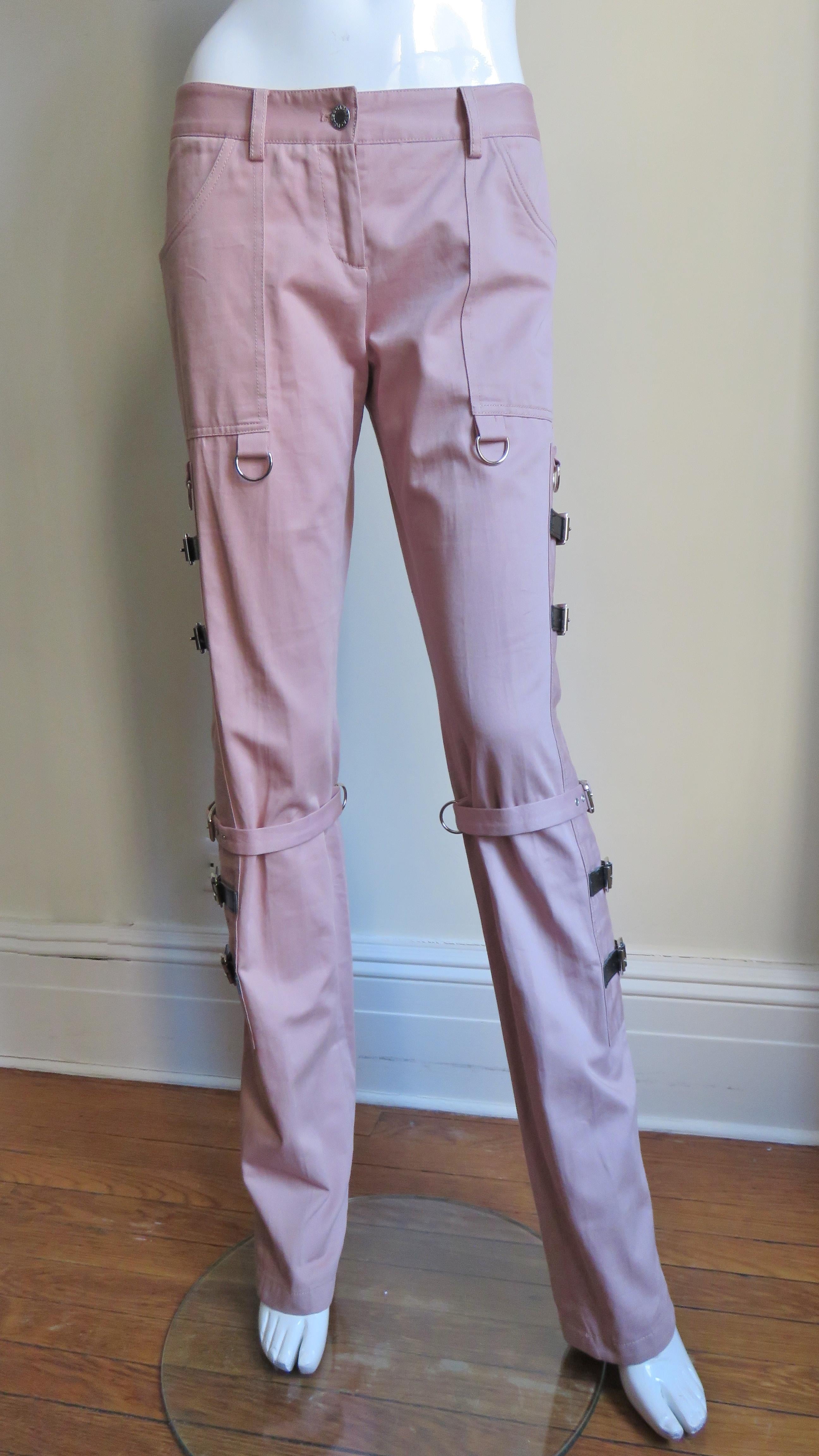 Beautiful pink cotton pants from Dolce & Gabbana.  They have a fly front button waistband with belt loops and side patch pockets.  Below the pockets are side panels almost the length of the pants with functional,adjustable leather straps and