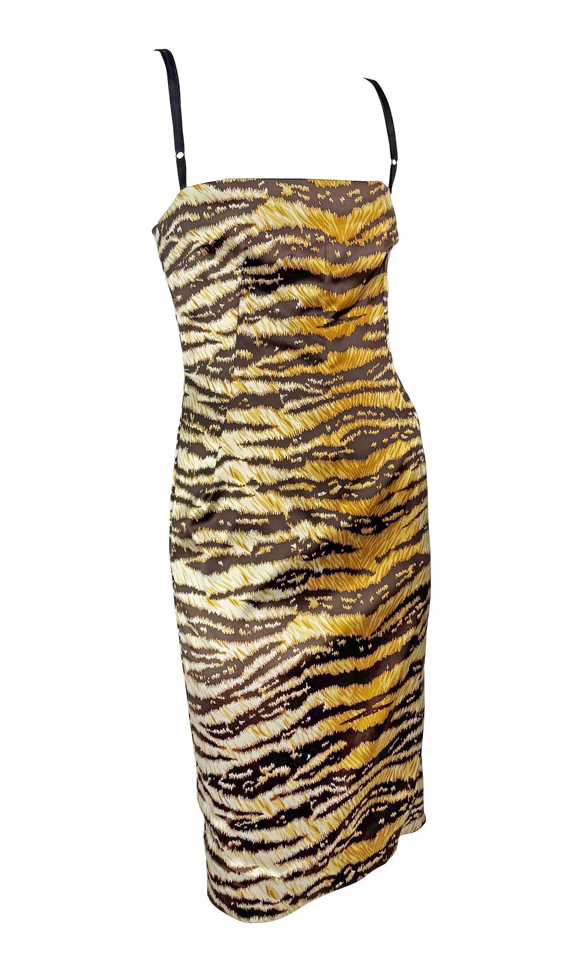 This 2000s Dolce & Gabbana midi dress features a striking tiger print on lustrous satin. The form-fitting silhouette is enhanced by delicate bra-style straps, a structured bust, and a back slit for ease of movement. The concealed side zipper ensures