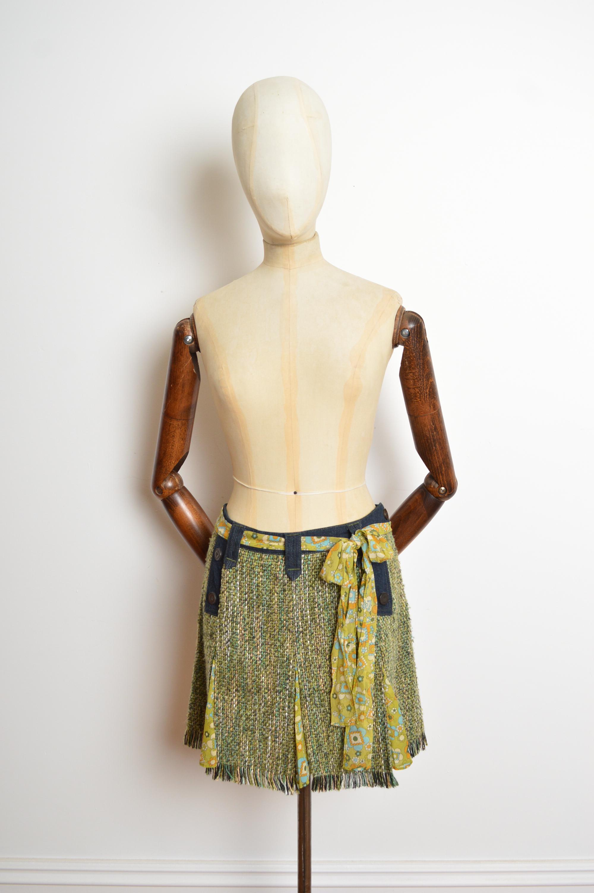 Una divertida minifalda Tweed & Denim de los años 2000 con detalles florales psicodélicos. La falda tiene botones en la parte delantera, cinturón desmontable (que también puede usarse como pañuelo, como se ve aquí), bolsillos delanteros ocultos y