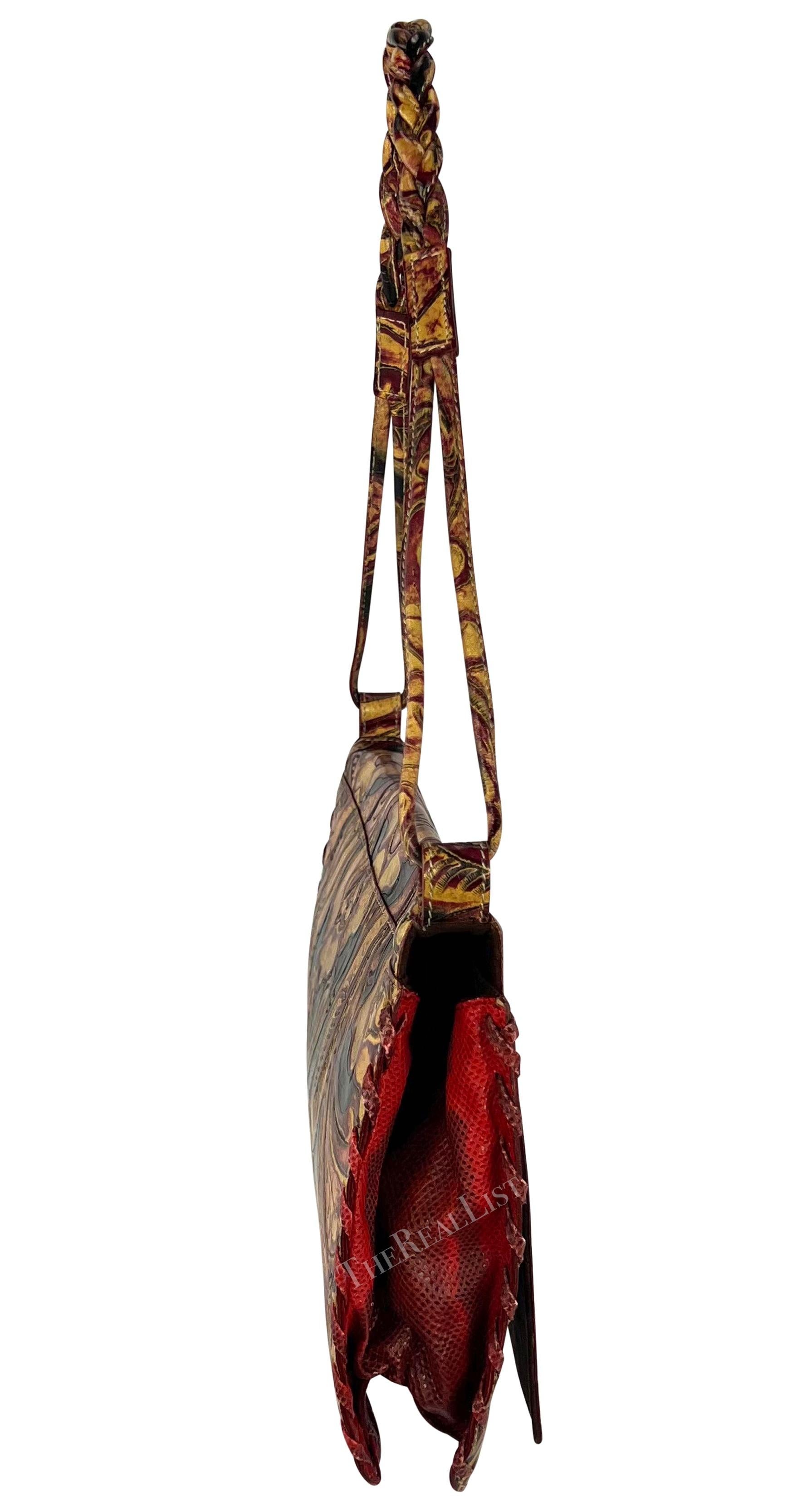 Presenting a tan and red carved leather Emanuel Ungaro shoulder bag. From the early 2000s, this chic bag is constructed entirely of tan, red, and black leather with a carved floral pattern. The bag is made complete with a flap closure, a thin