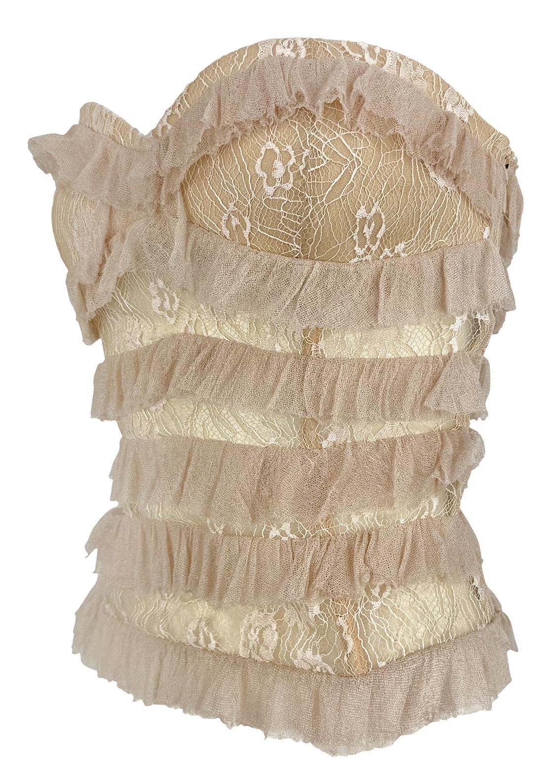 This beige Emanuel Ungaro strapless corset top from the 2000s is crafted from sheer floral lace and features structured boning throughout. Accented with romantic tiered ruffles and a lace-up closure at the back, this piece offers a feminine