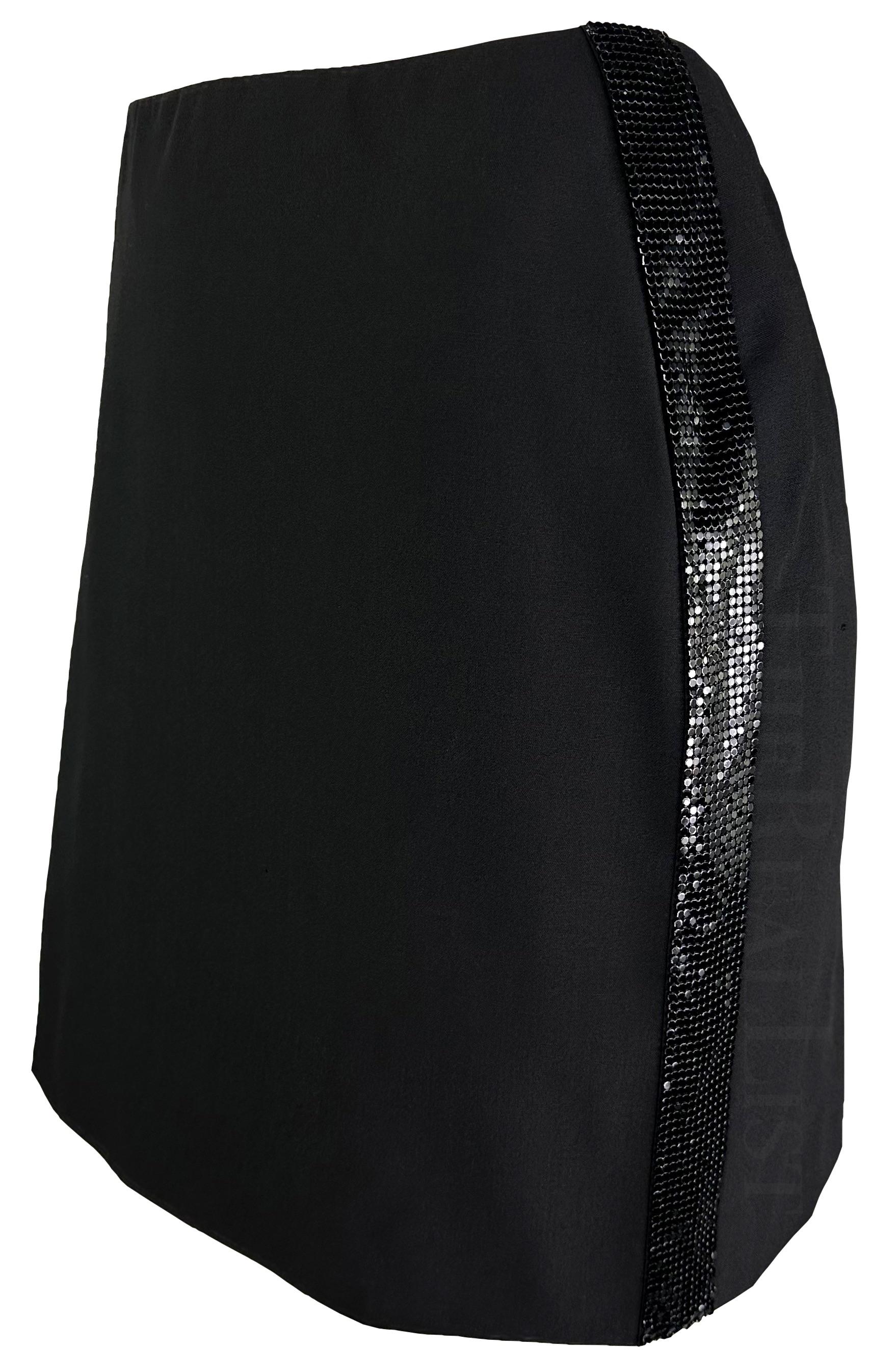 Présentation d'une mini-jupe noire chic de Gianni Versace, dessinée par Donatella Versace. Datant de la fin des années 1990/début des années 2000, cette jupe présente l'emblématique cotte de mailles Oroton de la maison, brevetée par Gianni en 1982.