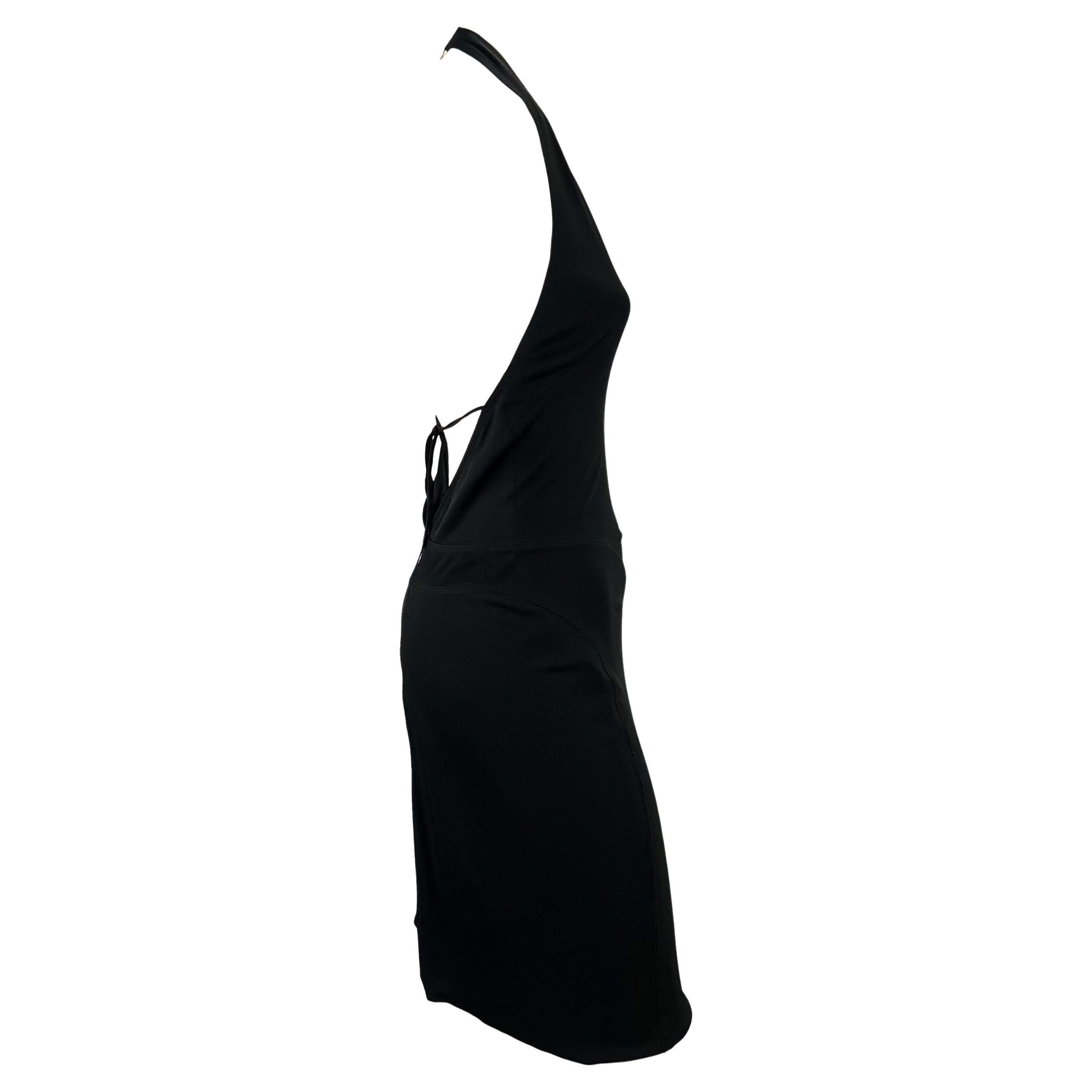 Présentation d'une robe dos nu stretch noire Gianni Versace conçue par Donatella Versace. Cette fabuleuse robe de la collection printemps/été 2002 présente un décolleté en V plongeant, un dos nu avec un lien autour de la taille et une fermeture en