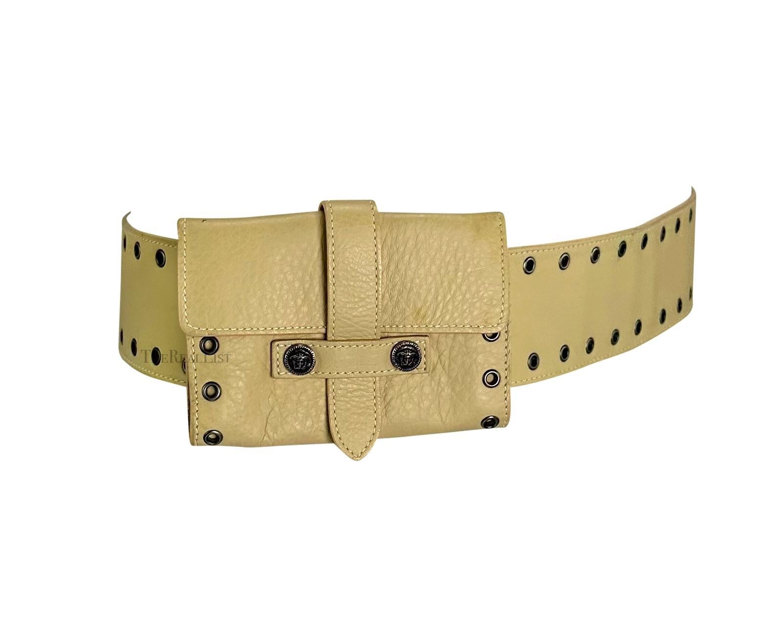 Presenting a fabulous light beige Gianni Versace leather waist bag belt, designed by Donatella Versace. From the early 2000s, this wide leather belt features a removable small envelope pouch, gunmetal eyelets, an adjustable peg closure, and two