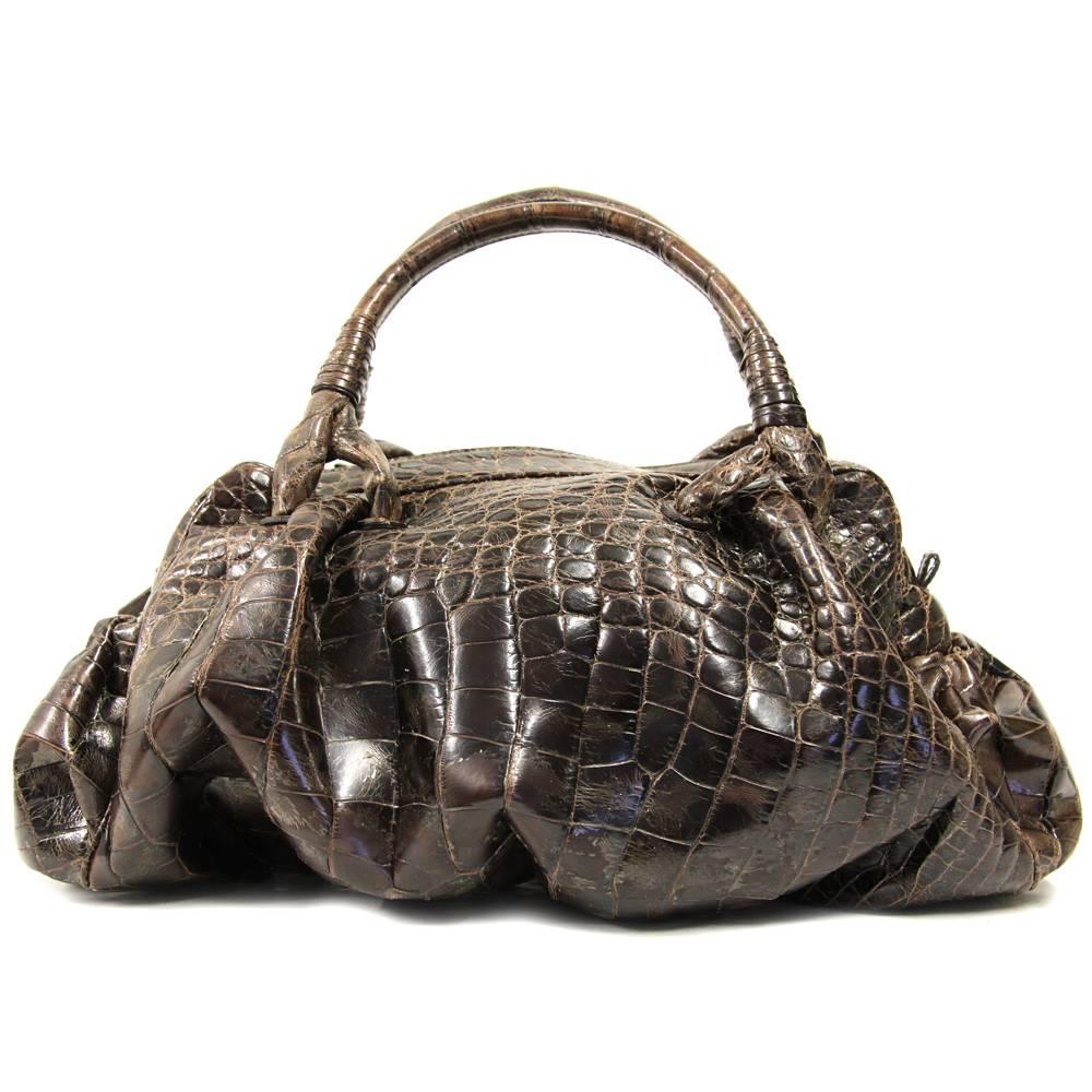 Luxurious Giorgio Armani bag in soft, glossy chocolate brown crocodile leather. Handles are perfect to carry it by hand. Designed with coffer and pockets on the sides, a small metal charm with brand logo. Features a zip closure and suede lining.