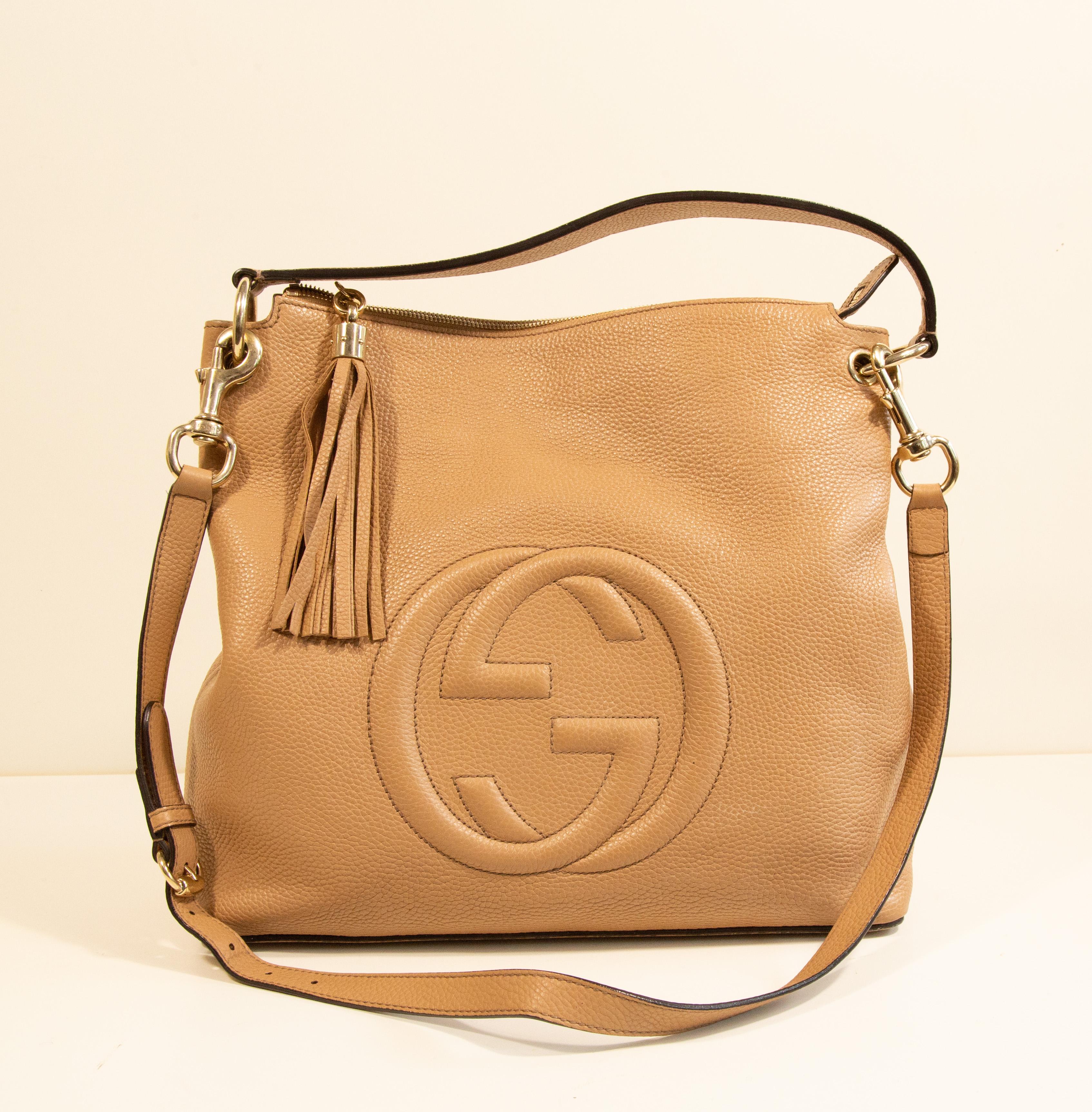 Borsa convertibile SOHO di Gucci in pelle beige con finiture dorate. L'interno è foderato in tessuto beige e, accanto allo scomparto principale, presenta tre tasche laterali di cui una con cerniera. La borsa si chiude con una cerniera.  La borsa può