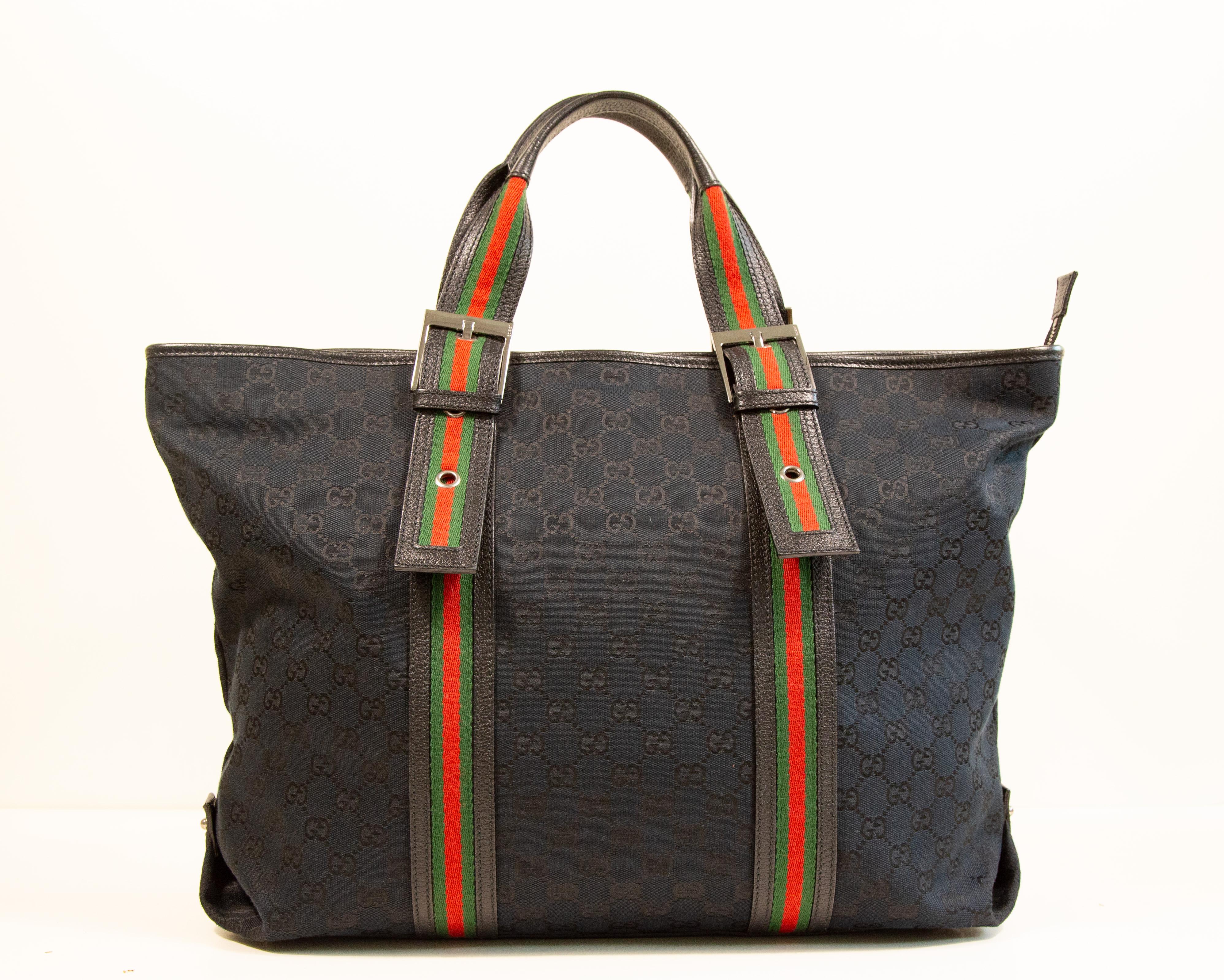 Una grande borsa Gucci in tela nera GG Guccissima con finiture in pelle nera, finiture in peltro lucido e la tracolla firmata Gucci all'esterno e sui manici. La borsa può essere chiusa con una cerniera. L'interno è foderato in tessuto nero e,