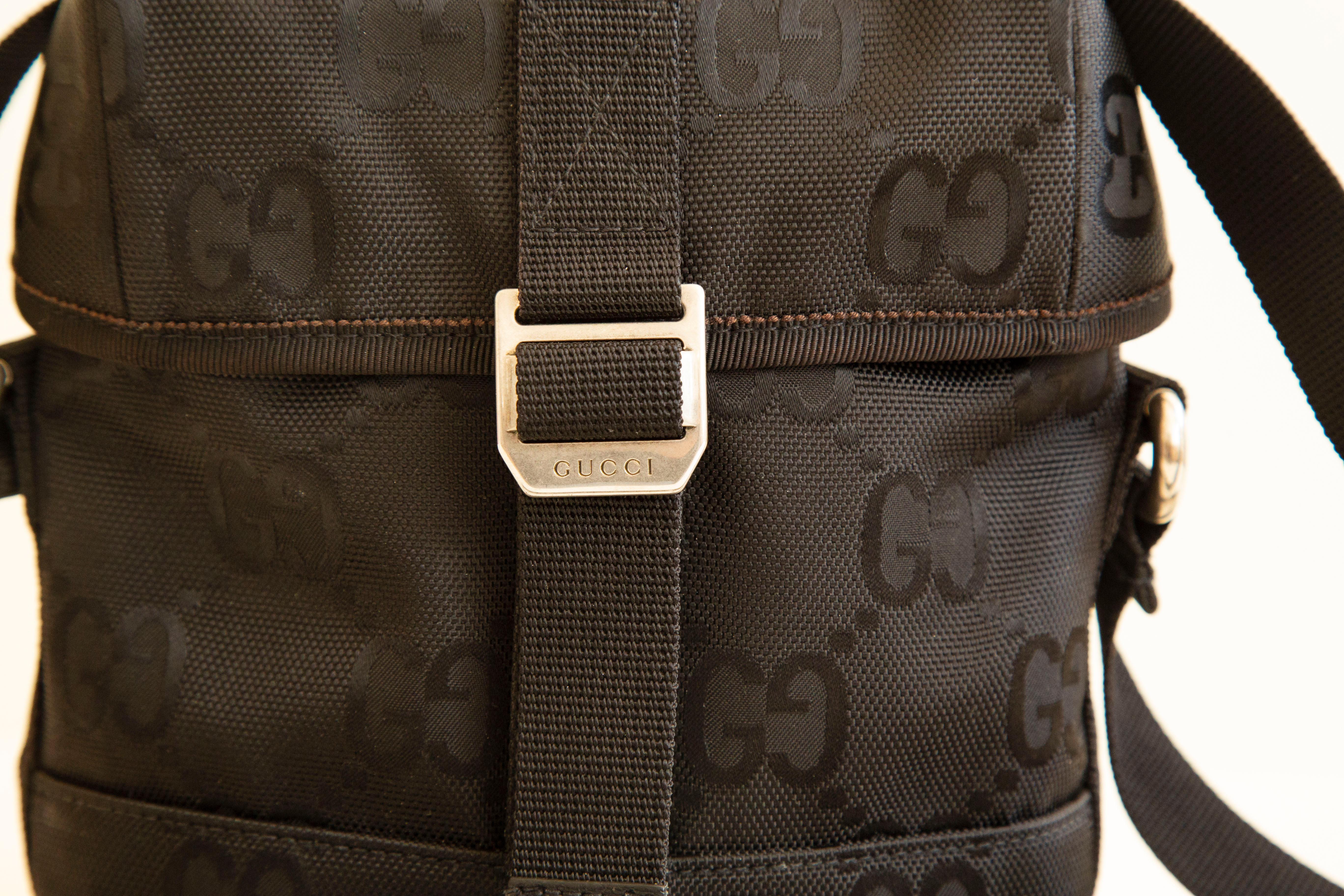 A Gucci men's bag made of black GG embossed nylon and silver tone hardware.The interior is lined with black smooth nylon and it features one compartment. The canvas strap is in length adjustable (max. 110 cm). The bag will be delivered with the
