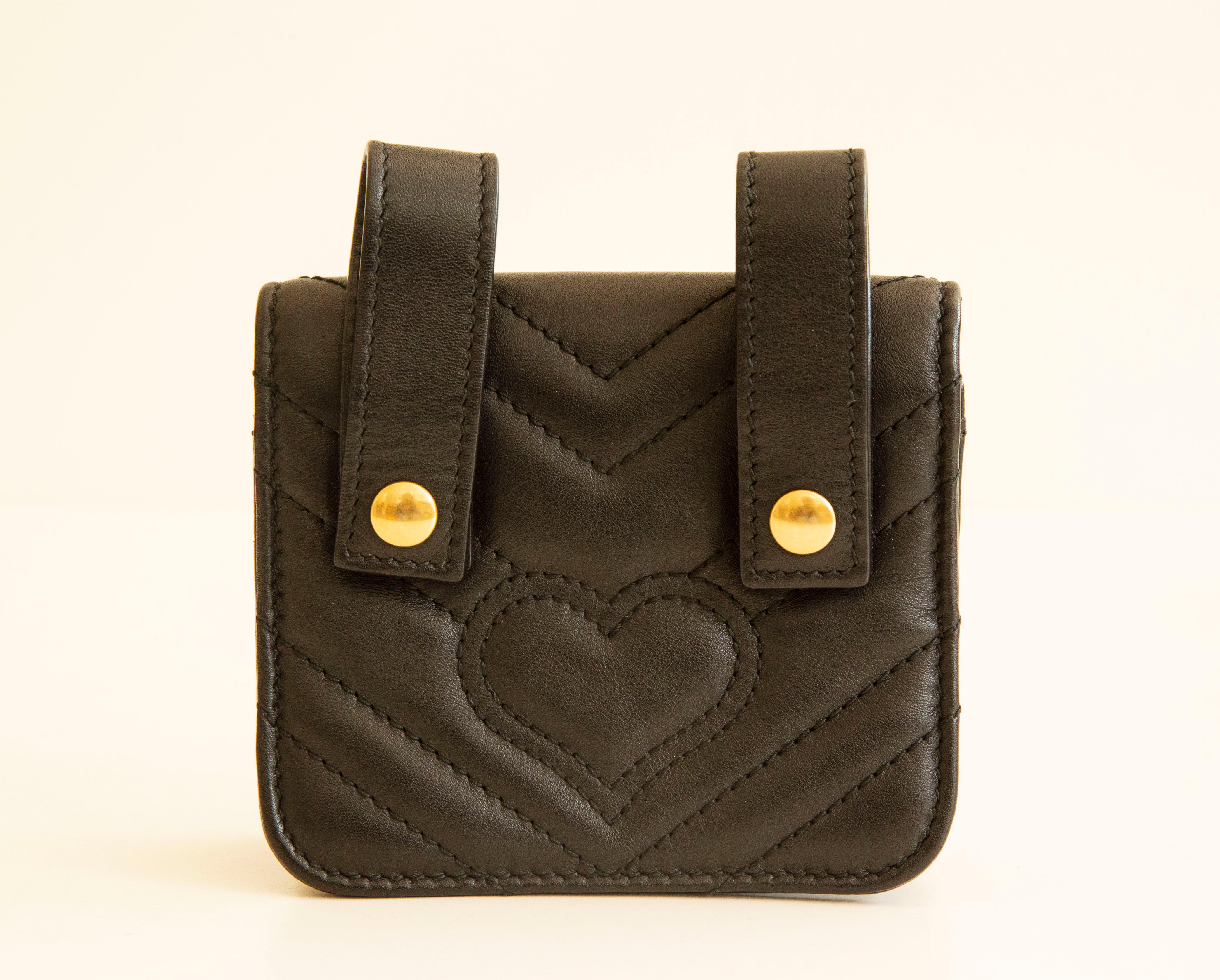 Black 'GG Marmont' quilted belt pouch from Gucci. It is made of black leather.  The belt pouch features a decoration of animal studs and logo made of antique gold-toned metal. The bag can be attached to a belt by two leather loops with snap buttons.