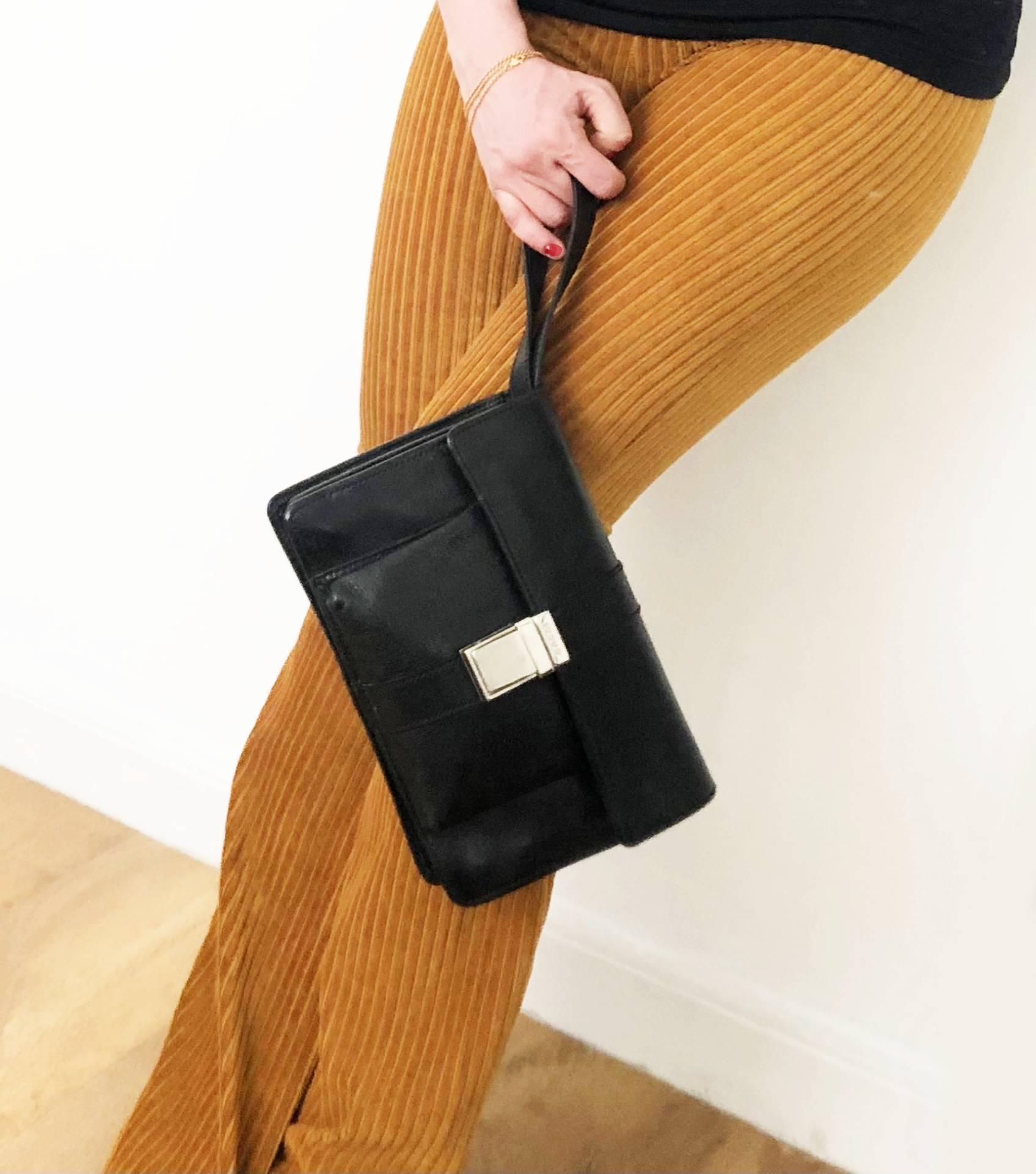 Black leather clutch flap over bag from Gucci featuring front pocket and 3 internal compartments, zipped internal pocket, cards compartment, pen holder, steel front clutch closure, hideaway wrist strap

 Measurements: 26.5x19x7.5cm 

Condition: 