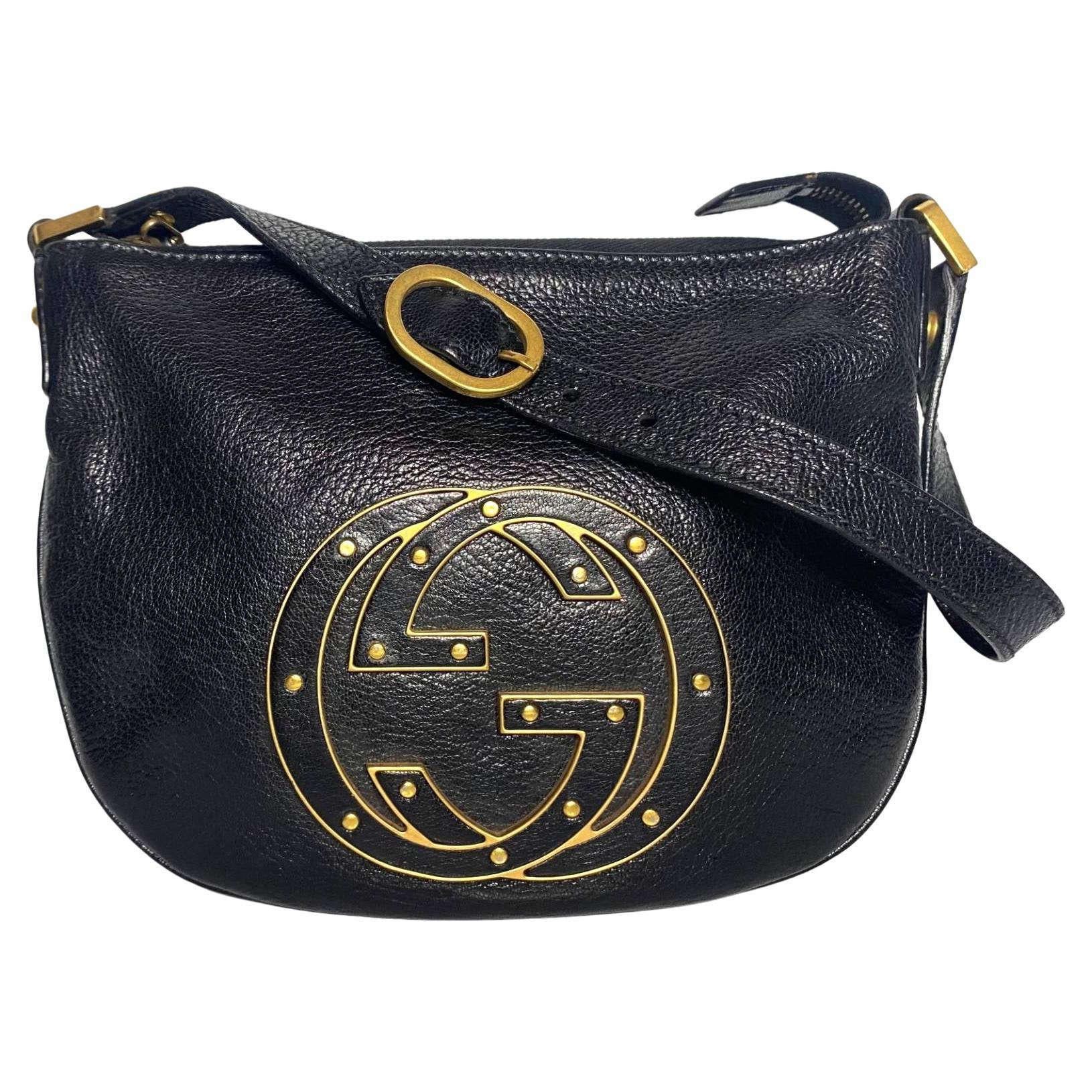 Tom Ford for Gucci small Blondie Hobo Bag, crafted of luxurious black leather and features a looping, side to side shoulder strap with polished light brass links and an adjustment buckle and a prominent brass and leather interlocking Gucci GG