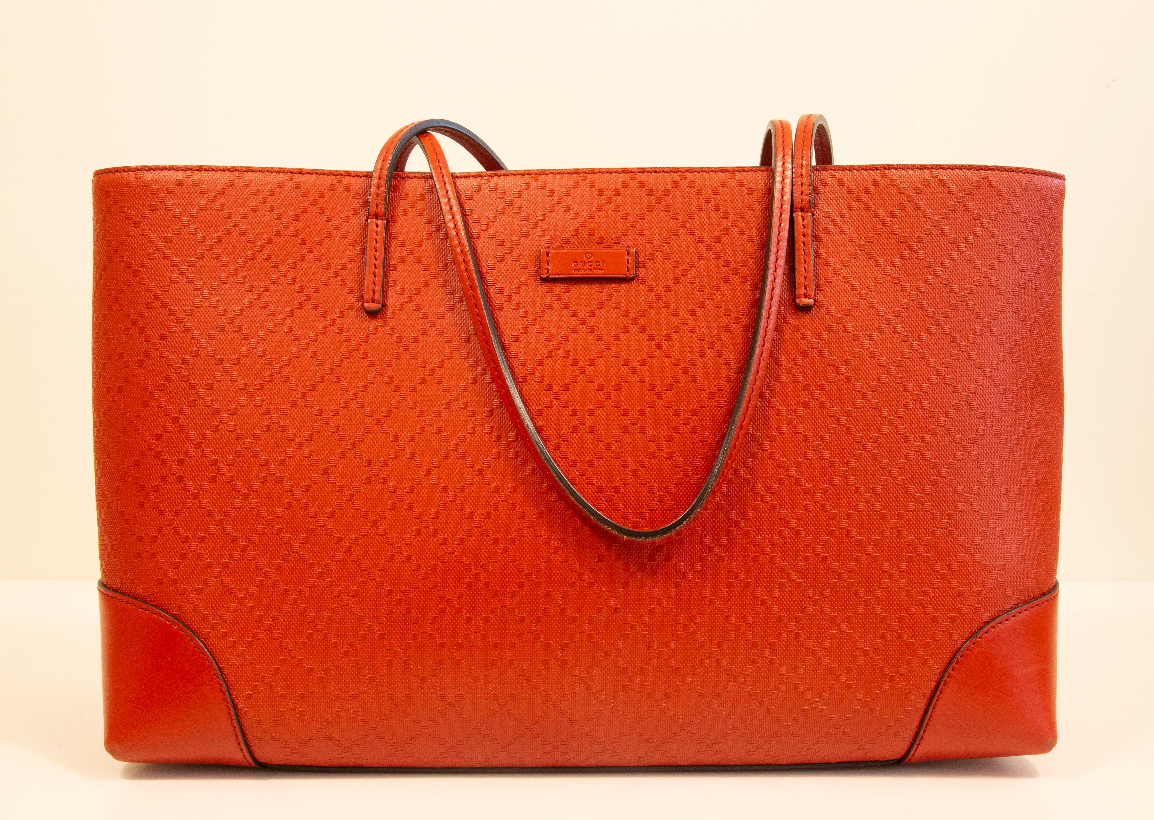 A Gucci Diamante Lux Tote bag made of vivid red leather. The bag is lined with brown fabric. Next to the major compartment, it features three side pockets of which one has a zipper. The bag has minor signs of use such as light discoloration of the