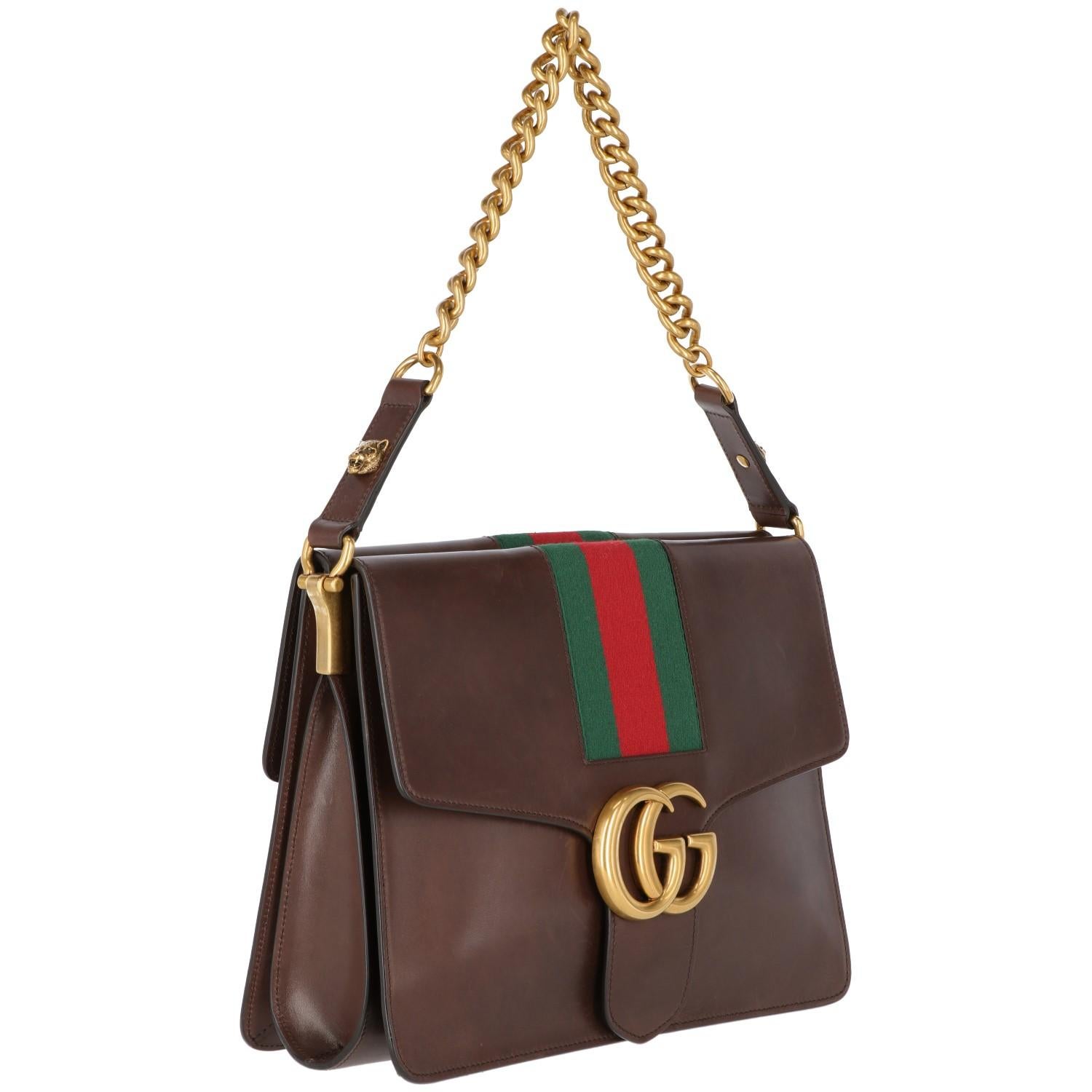 The iconic red and green central stripe Gucci bag, recently produced,  features a gold-tone front logo and fancy lion decorative details on shoulder strap. With two large pockets on both sides, an elegant green leather lining and the shiny gold-tone