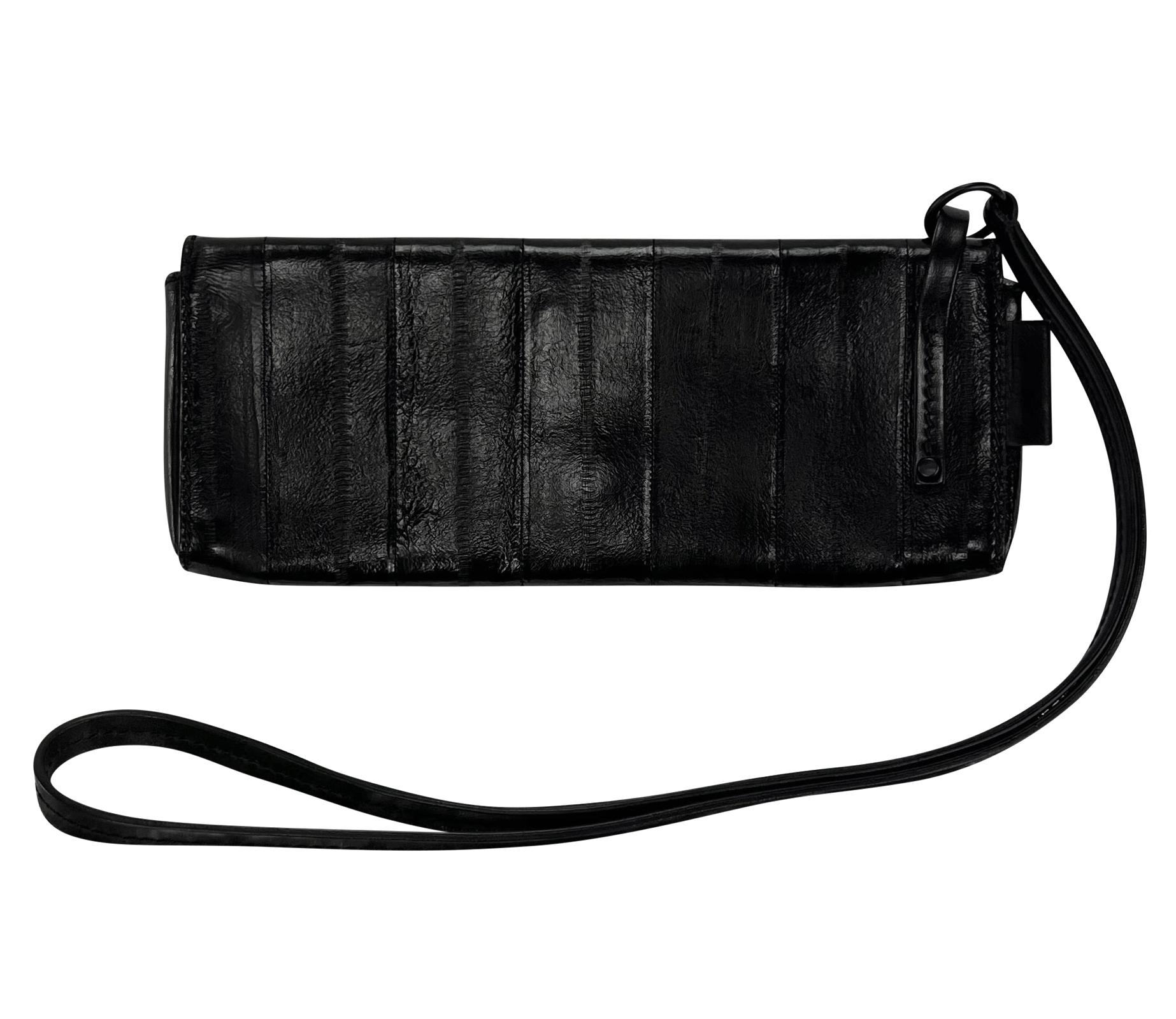 Designed by Tom Ford for Gucci in in the early 2000s, this sleek wristlet clutch is crafted entirely from shiny black eel skin. The bag features a flap closure and comes with a long strap for versatile carrying options.

Approximate