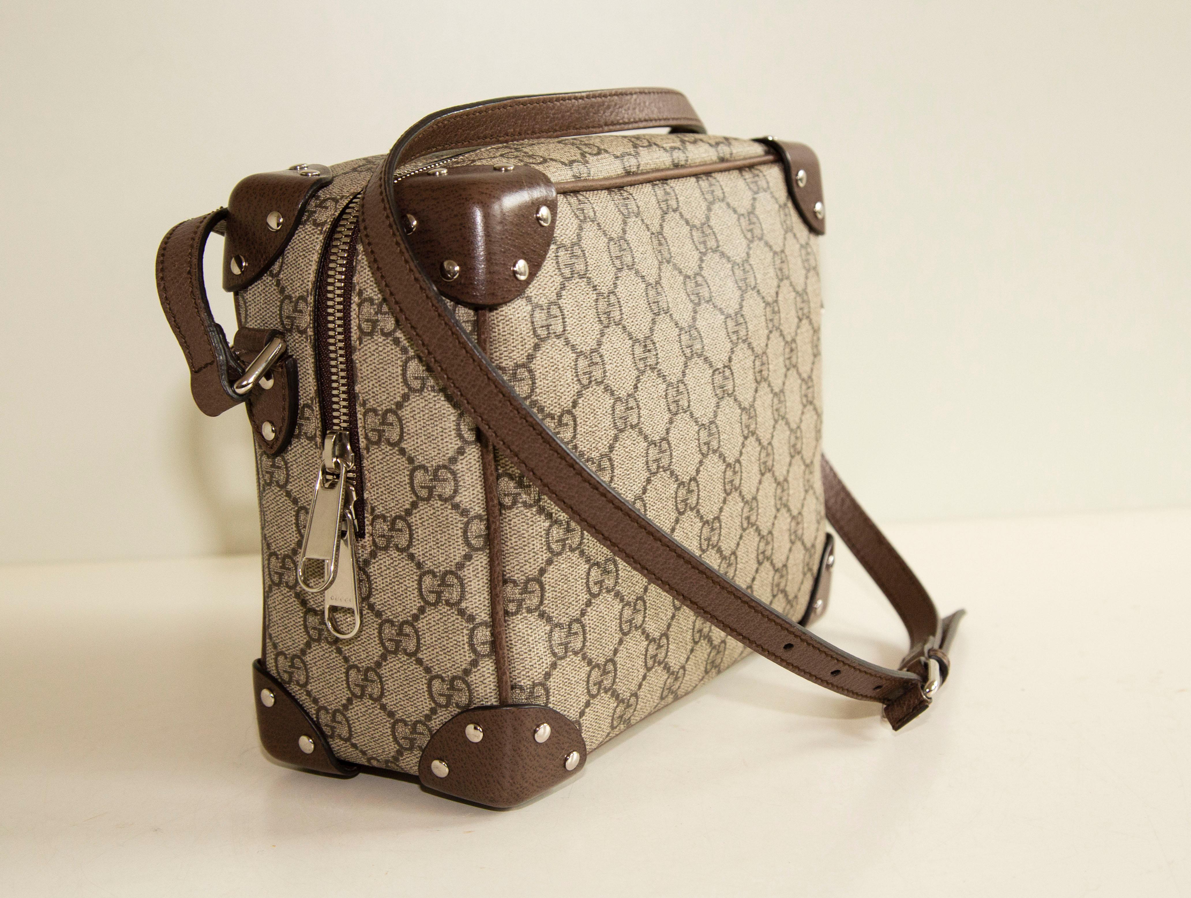 Gucci GG Supreme Monogram Square Shoulder Bag in Beige and New Acero. The bag is made of Broen Gucci GG supreme monogram canvas and finished with brown leather trim and silver toned hardware. The interior is lined with dark red fabric, and next to
