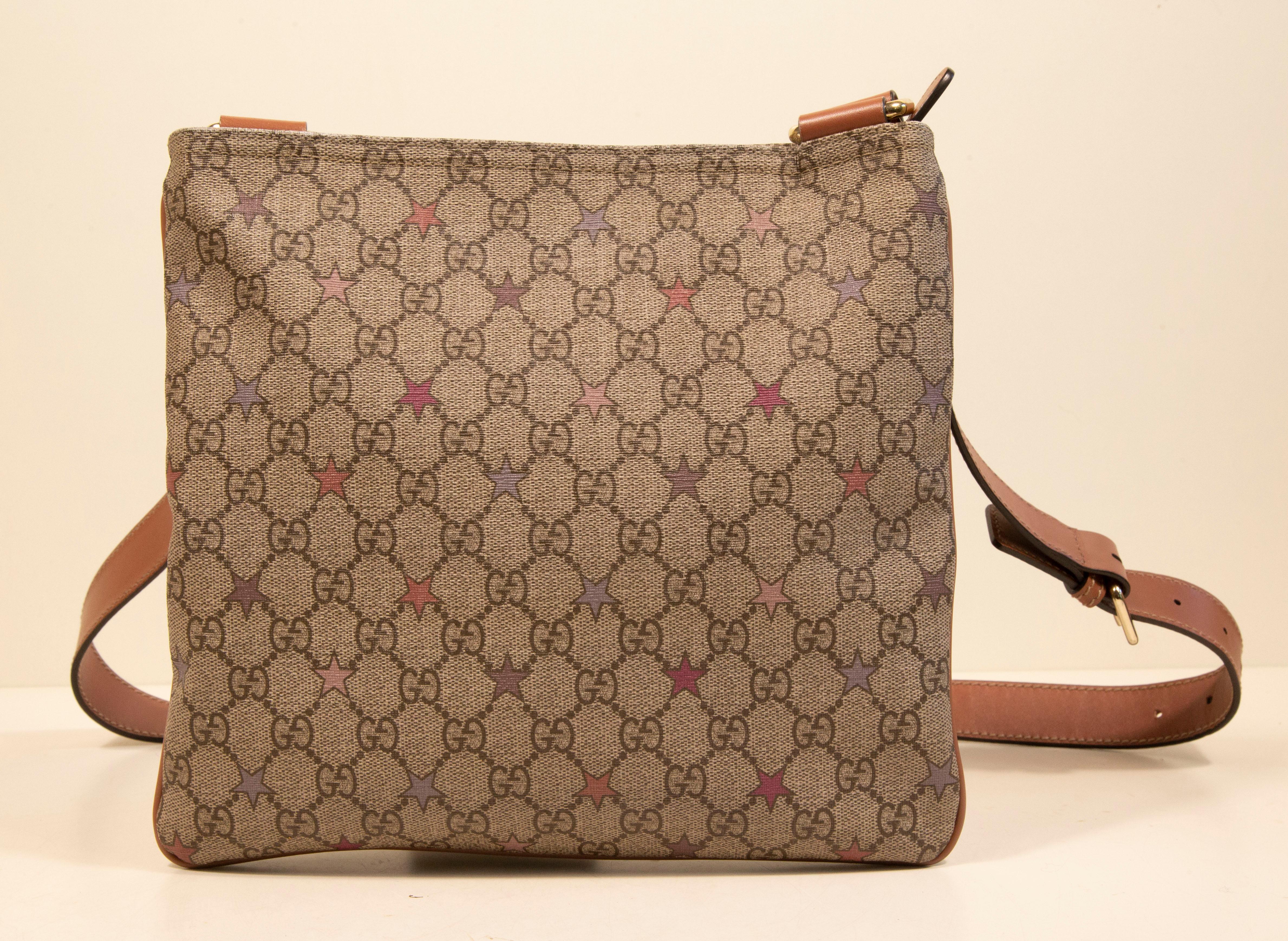 Gucci GG Supreme shoulder bag/crossbody bag made of vinyl coated canvas with light gold toned hardware and pink leather trim. The interior is lined with beige fabric, and next to the major compartment it features one side slide pocket. The bag