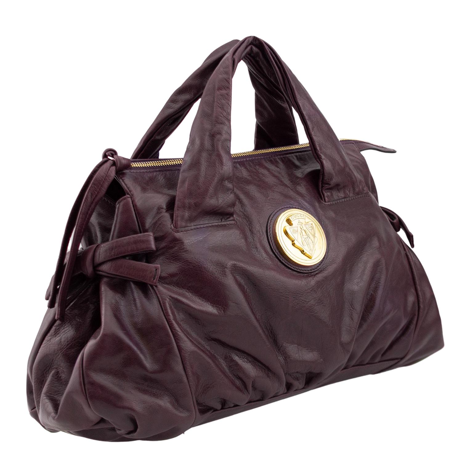 Gucci slouchy top handle bag from the early 2000's Hysteria collection. Maroon leather with contrasting gold tone hardware. Leather bow details on both sides, heavy zipper across the top with long matching leather pull and large round Gucci crest.