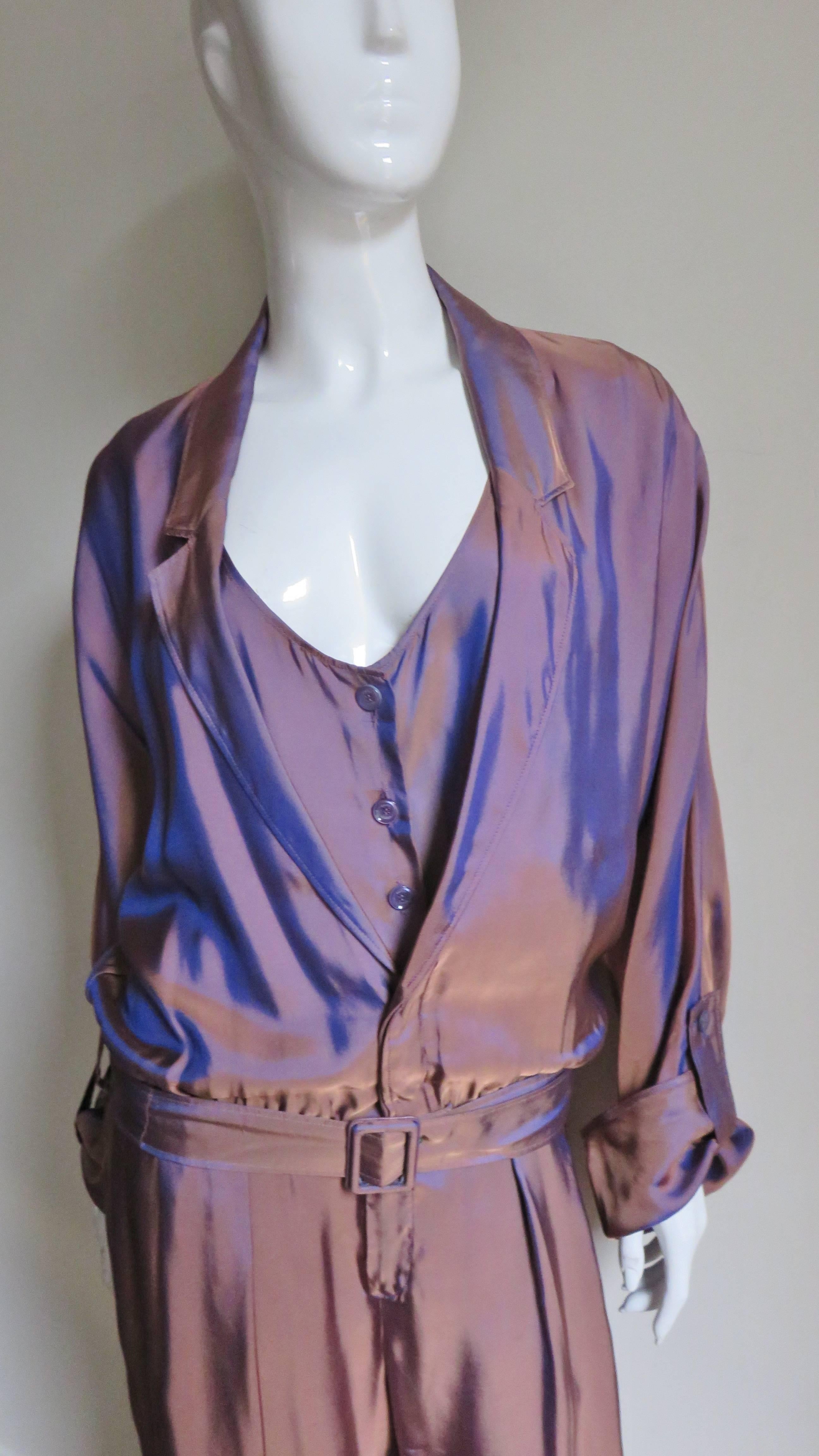 A gorgeous iridescent bronze silk jumpsuit from Gucci.  It has a plunging lapel collar over an attached low cut button vest in front. The dolman sleeves can be folded back at the cuffs and have button tabs on the outside to hold in place. The bodice