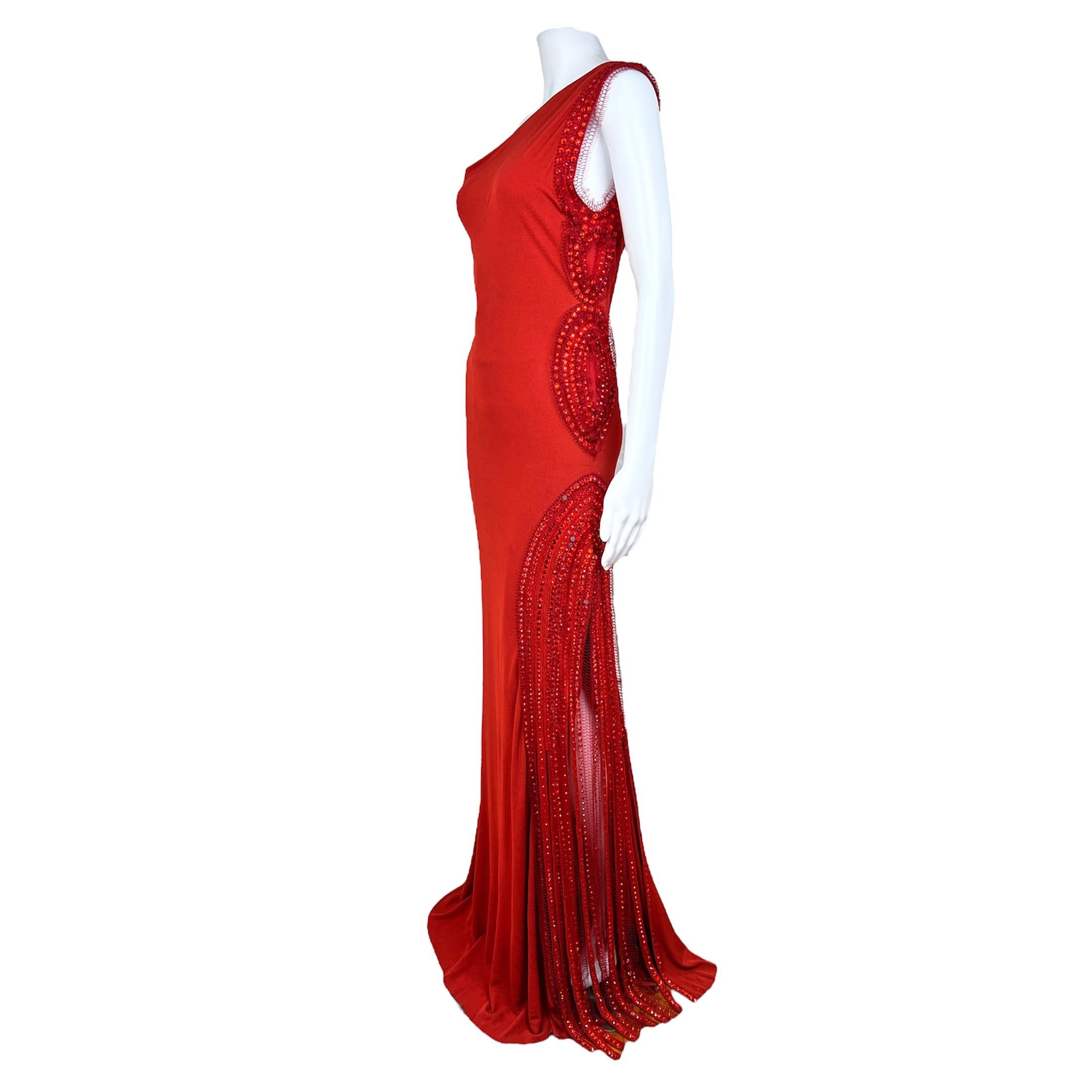 Gorgeous vintage Jean-Paul Gaultier one shoulder red gown with slit from the 2000s. The gown is made out of silk and mesh material and has beads appliqués and fringes on the left side of the body. The dress is completely lined with mesh material.