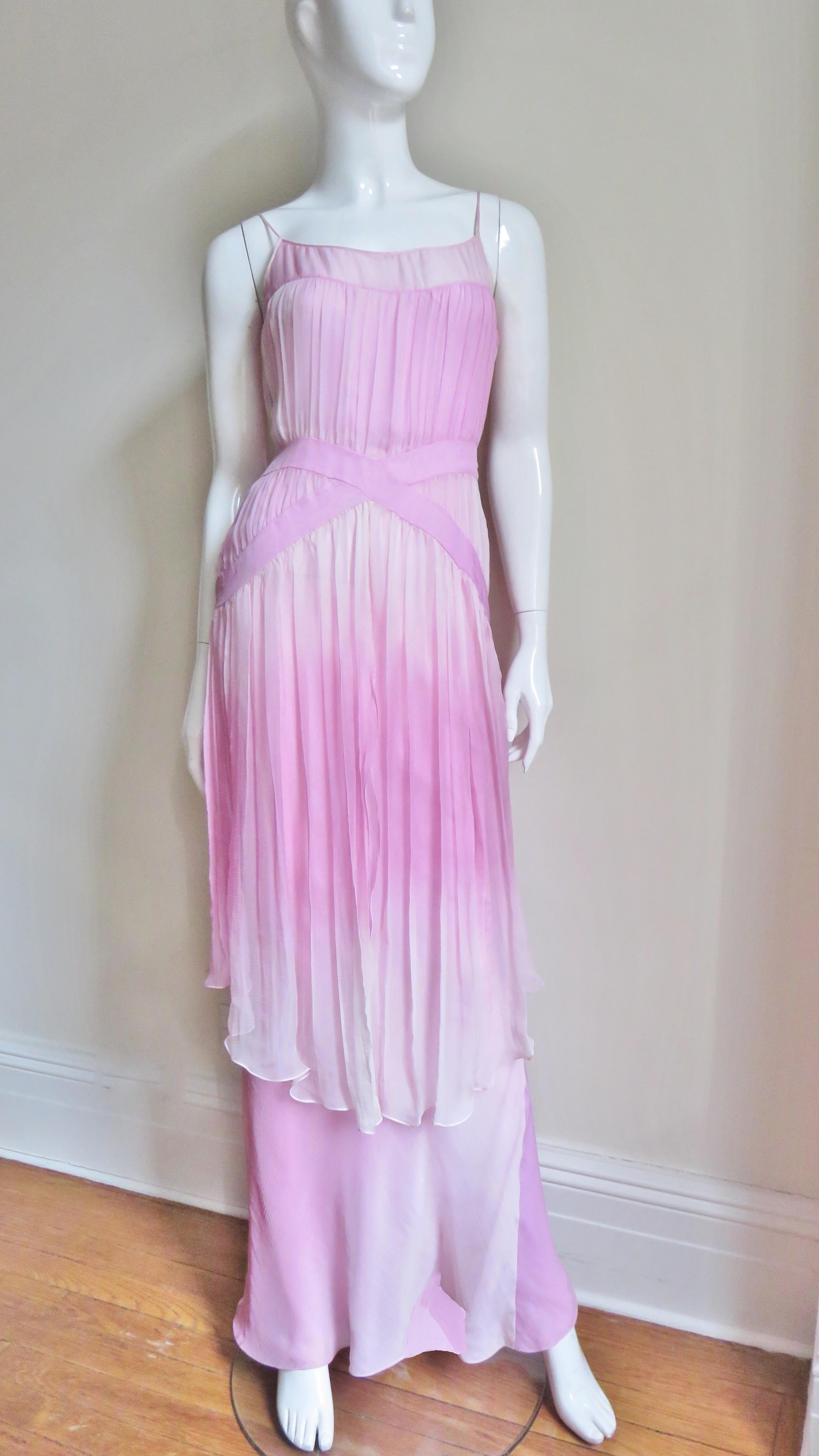 Une spectaculaire robe en soie de John Galliano dans des tons roses ombrés.  Le corsage a des bretelles spaghetti et se fronce sur deux bandes angulaires qui se croisent à la taille.  Elle comporte une jupe à deux niveaux, le niveau le plus court