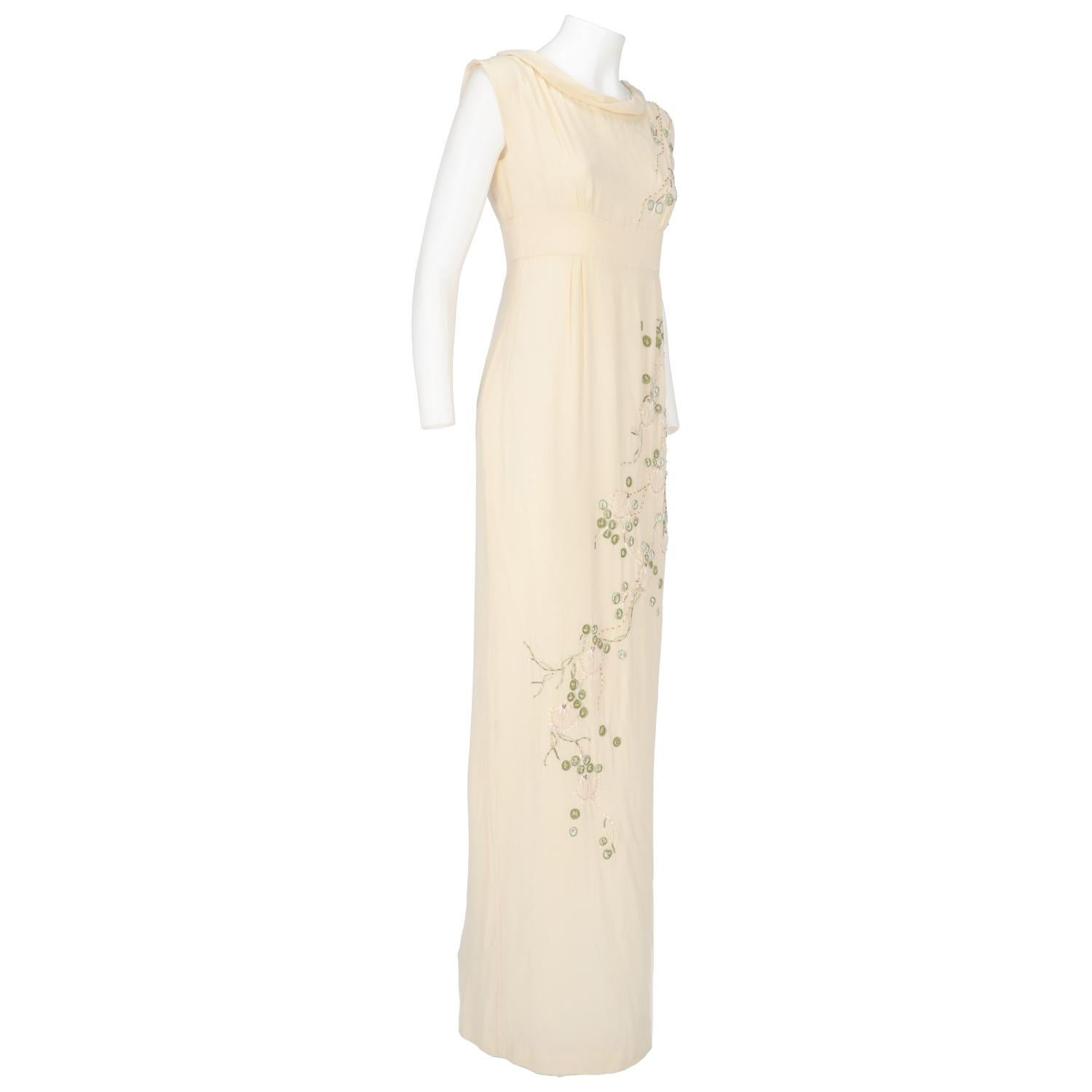 The elegant and romantic John Galliano ivory silk layered empire style wedding dress features a long slit on the side and a buttoned side fastening. The neckline is lightly wide and all the dress is embellished by silver-tone sequins, white pearl