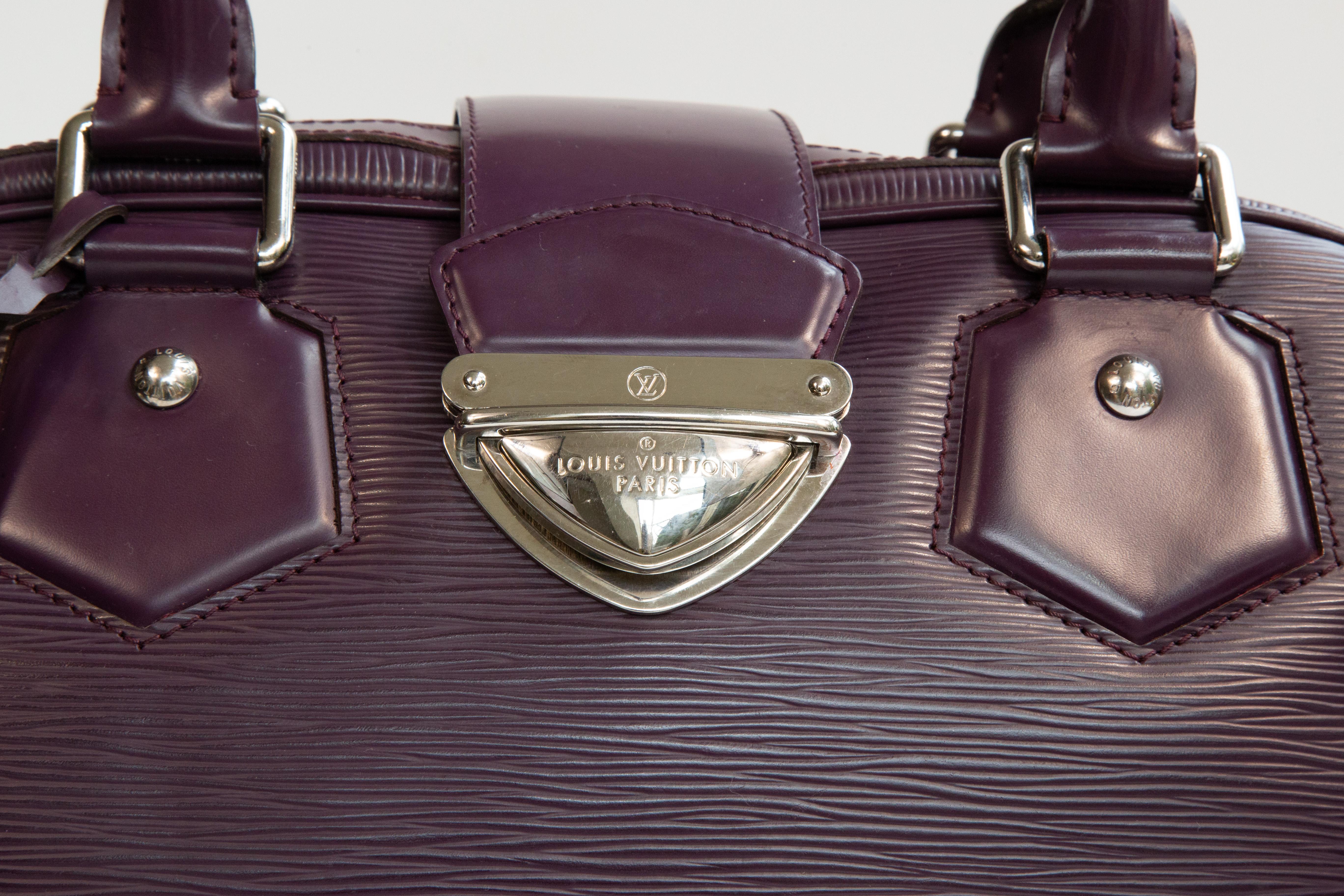 Sac à main Louis Vuitton Montaigne conçu par Nicolas Ghesquière. Le sac est réalisé en cuir épi violet avec des ferrures argentées. L'intérieur est doublé d'un tissu violet et comporte, à côté du compartiment principal, deux poches coulissantes. Le