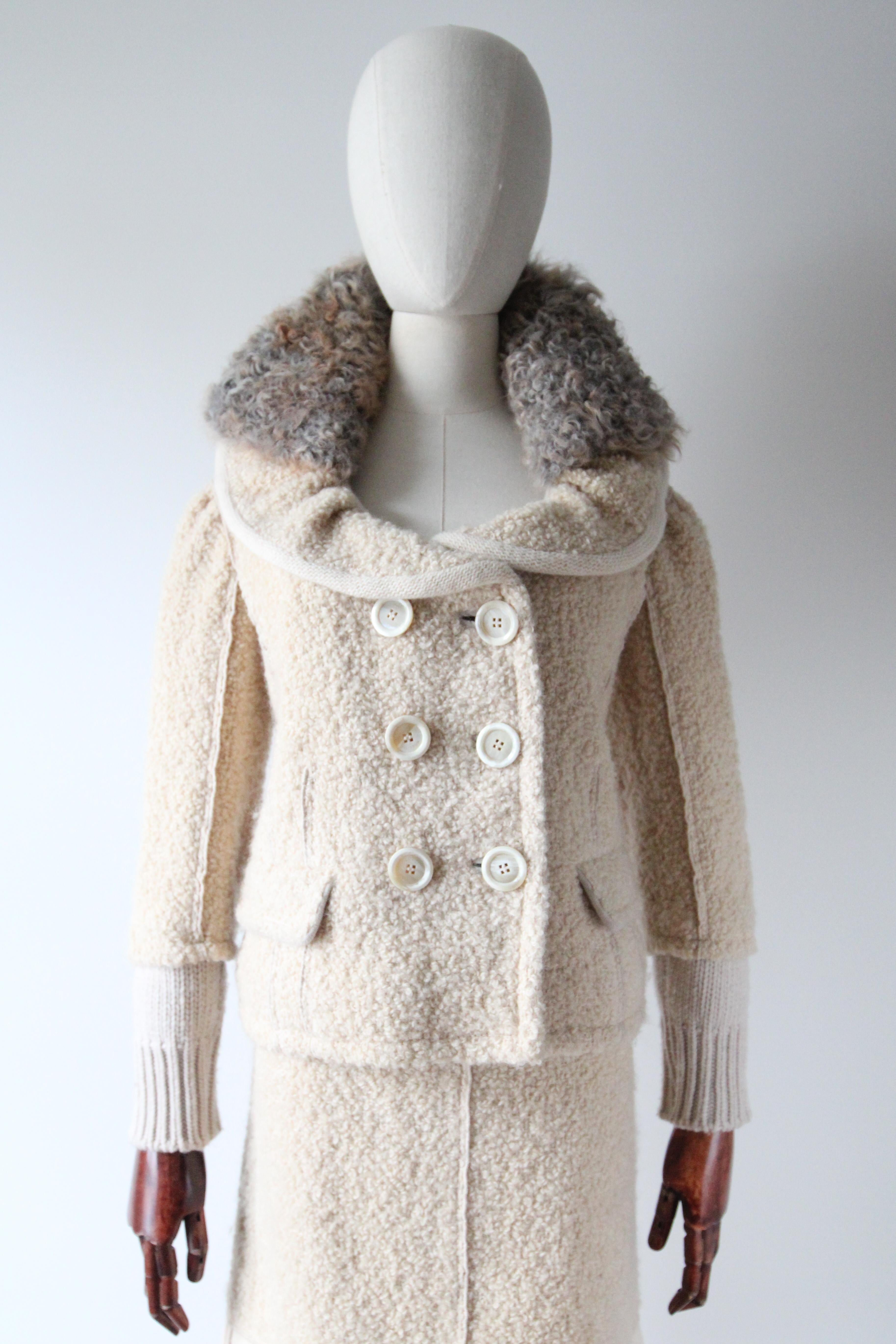 An iconic and timeless design. This original Louis Vuitton skirt suit, rendered in a cream bouclé wool, with a grey and taupe toned removable mohair collar, and knitted cream wool accents, is the perfect ensemble for the chillier weather. 

The