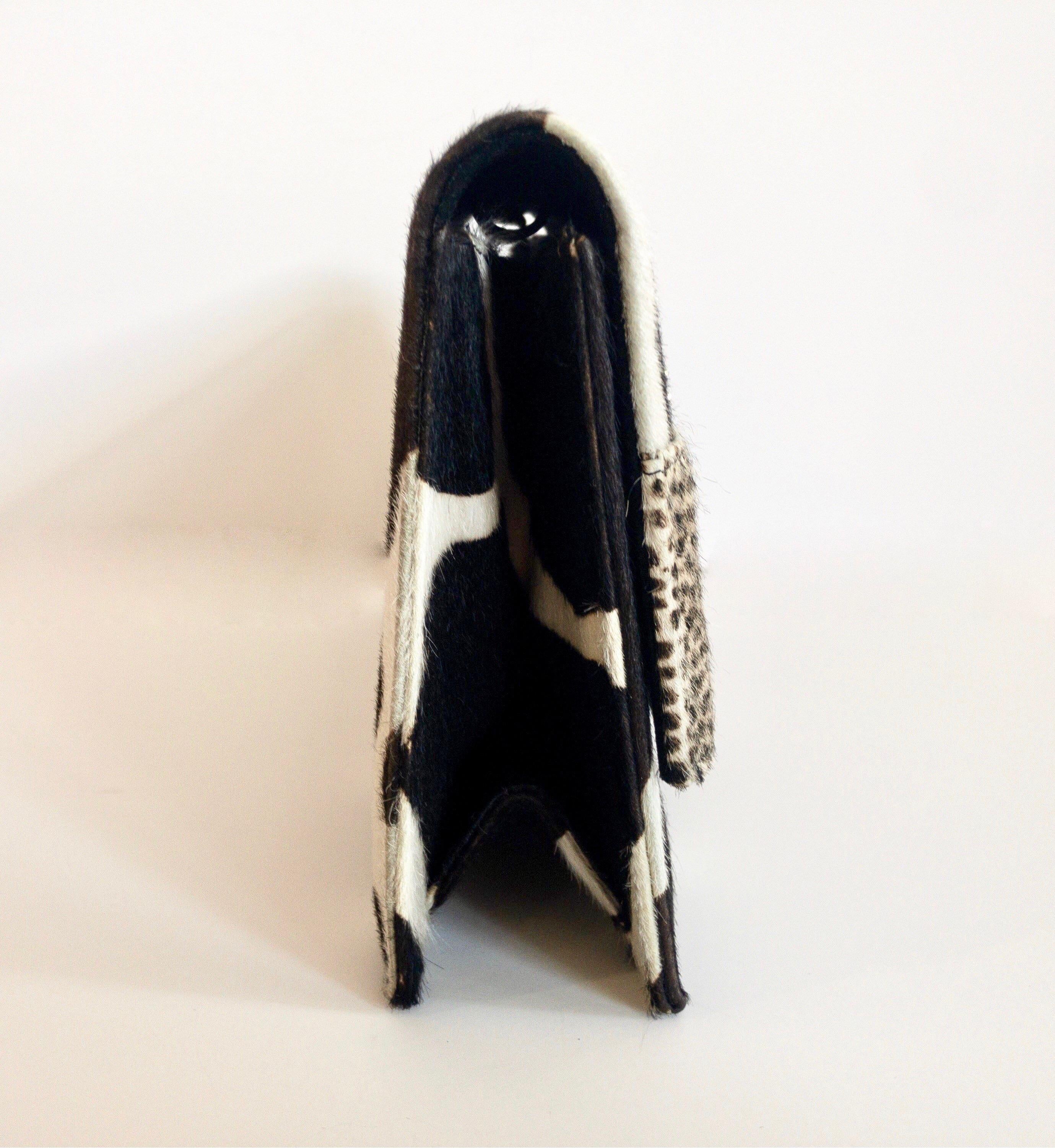 Complete your evening look with this Manolo Blahnik clutch! Circa 2000s, this clutch is made of calf hair and features contrasting cow print and cheetah print. Front exterior of clutch includes a belt style accent with a crystal embellished buckle.