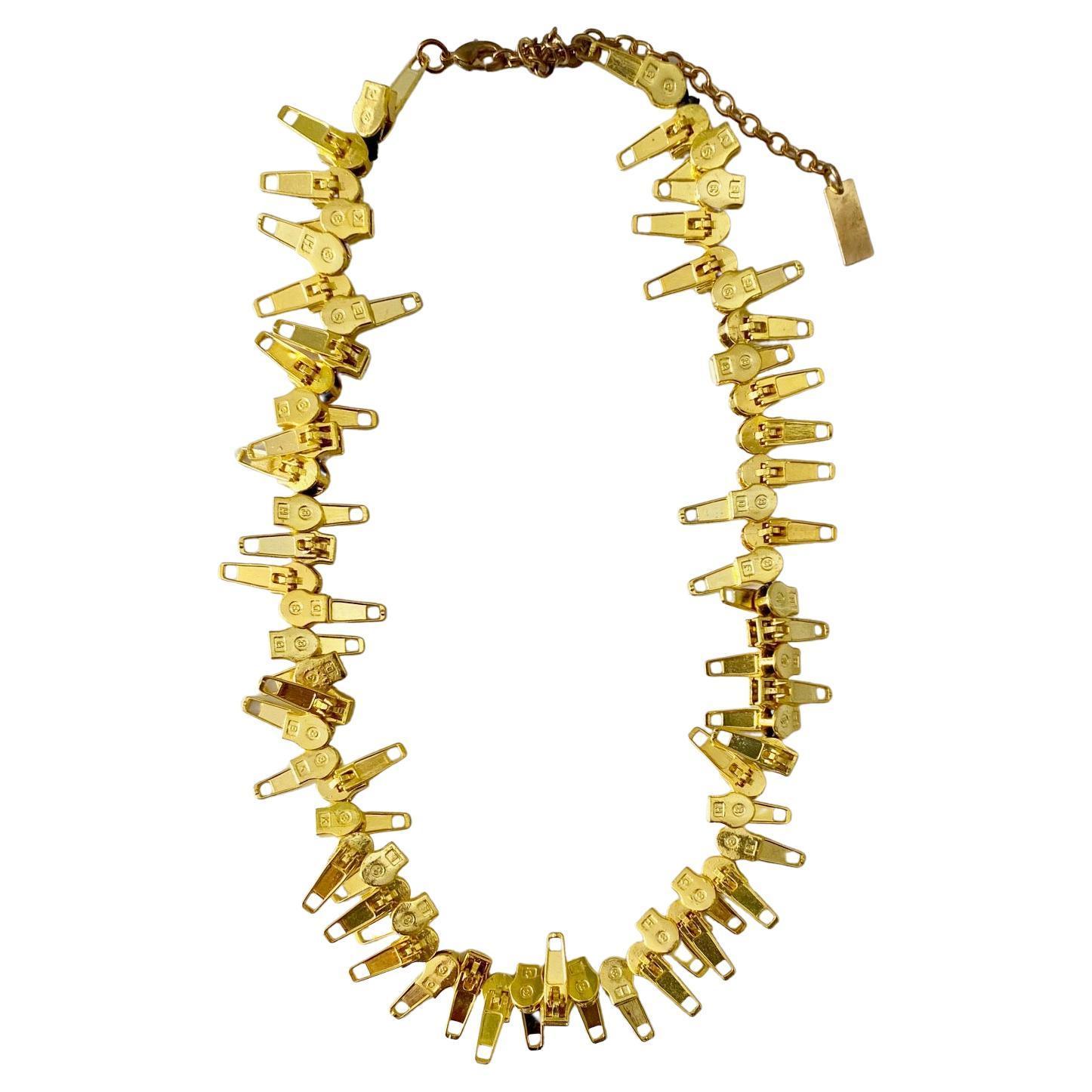 Diese Statement-Halskette von Marc Jacobs ist aus mehreren goldfarbenen Reißverschlüssen gefertigt und mit dem Signature-Stempel des Designers am Verschluss versehen. Sie ist in der Länge verstellbar und wird mit einem Karabinerverschluss und einem