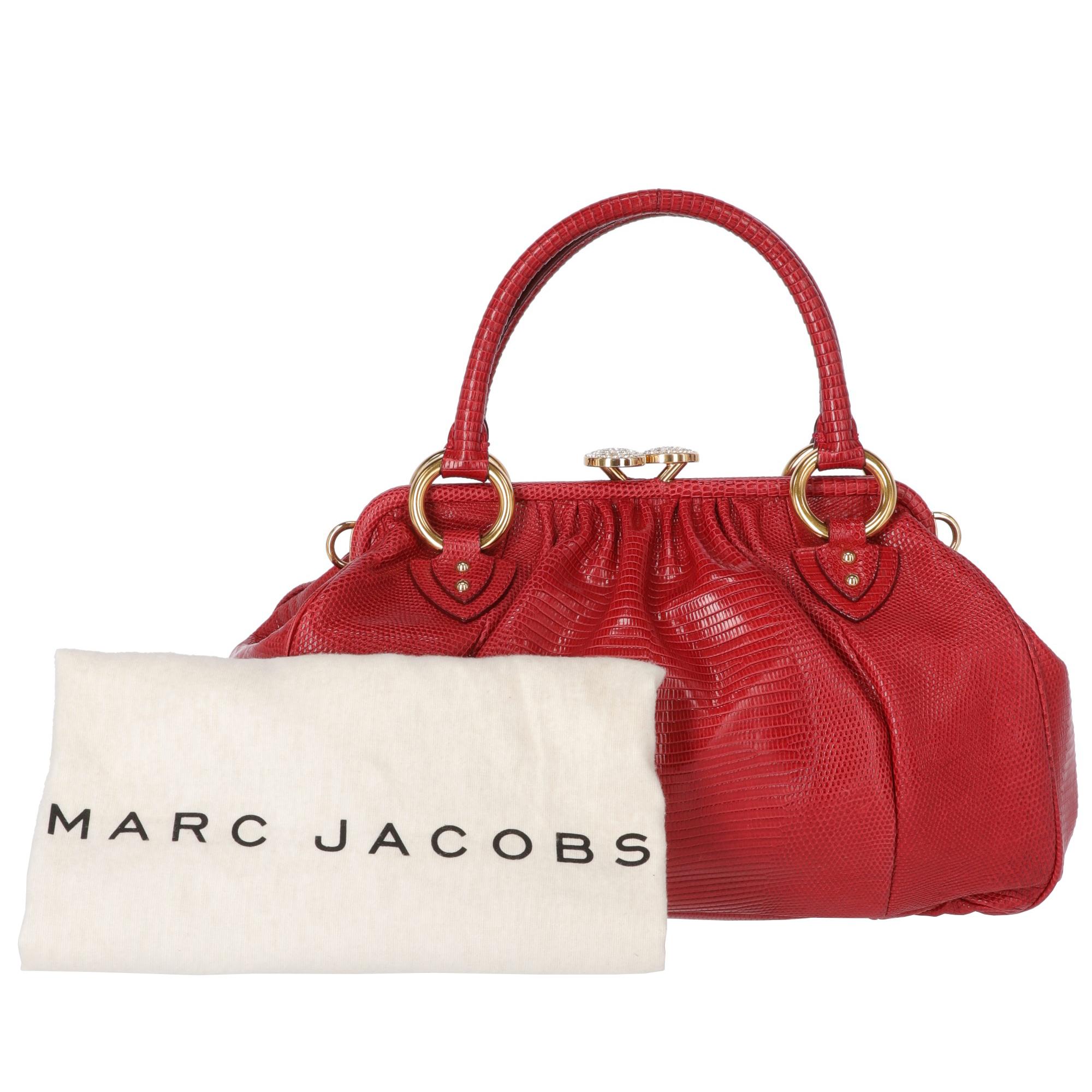 Marc Jacobs red tejus lizard handbag with two handles and gold-tone metal buckles and shoulder strap loops. With rhinestone and golden metal clasp closure, the bag features a front zip pocket with precious zip puller in metal and crystals. The