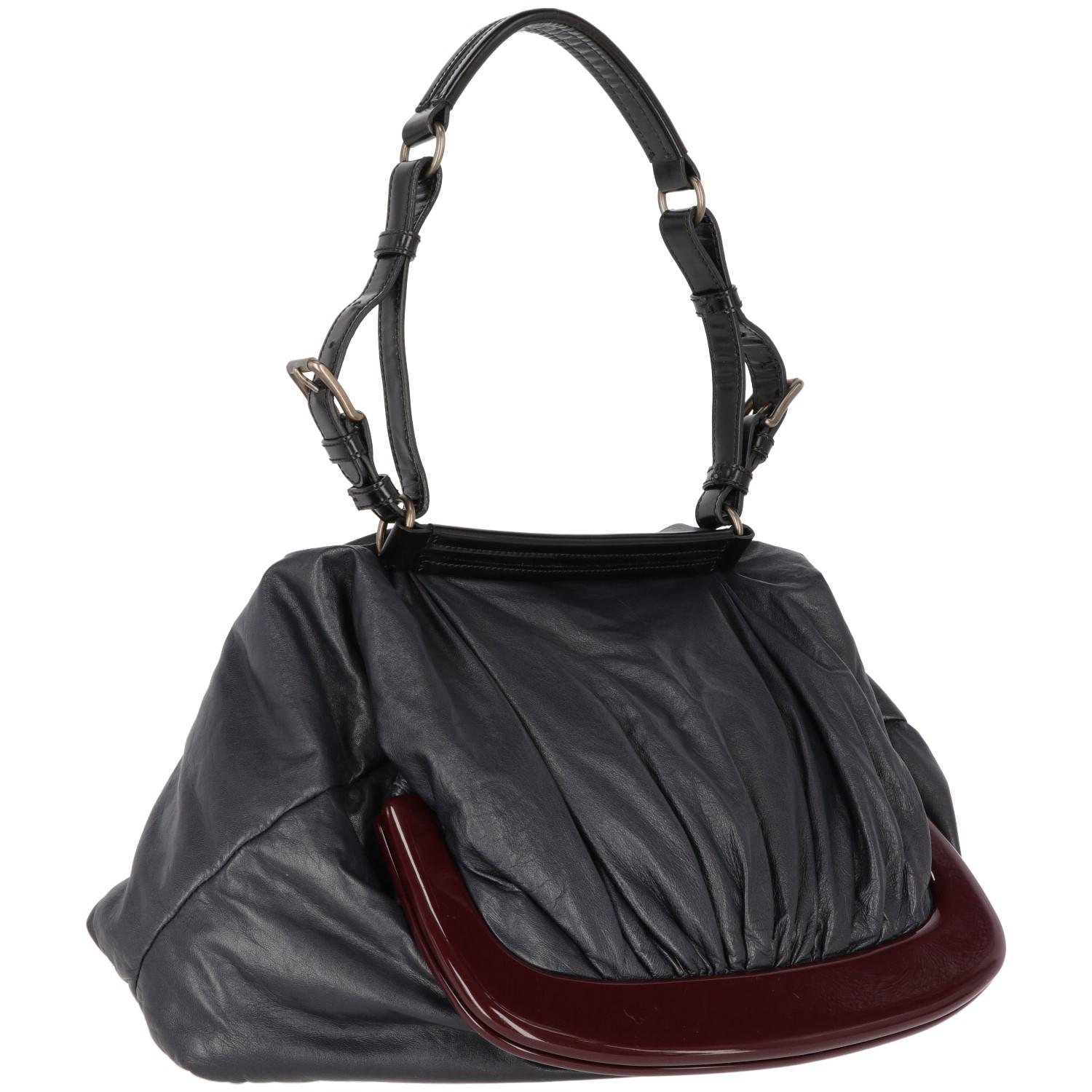 The original Marni blue nappa leather design tote bag  features a black leather handle and a bordeaux pvc clasp closure. 
The item shows scratches, as shown in the pictures.

Years: 2000s

Made in Italy

Width: 28 cm
Height: 44 cm
Handle: 57 cm