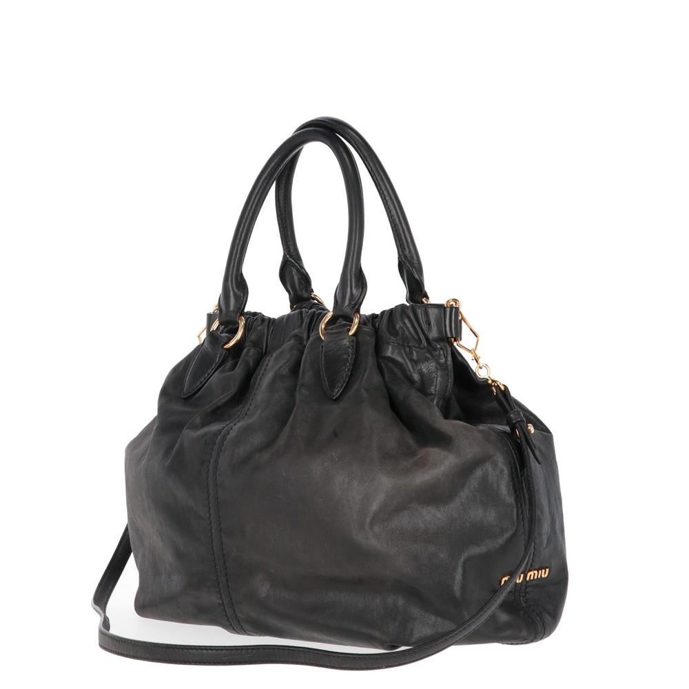 Miu Miu black leather tote bag with two handles and gold-tone hardware. Removable shoulder strap, elastic band and snap button fastening.
Bag shows signs of wear on the leather, as shown in the pictures. 

Years: 2000s

Height: 32 cm
Width: 41