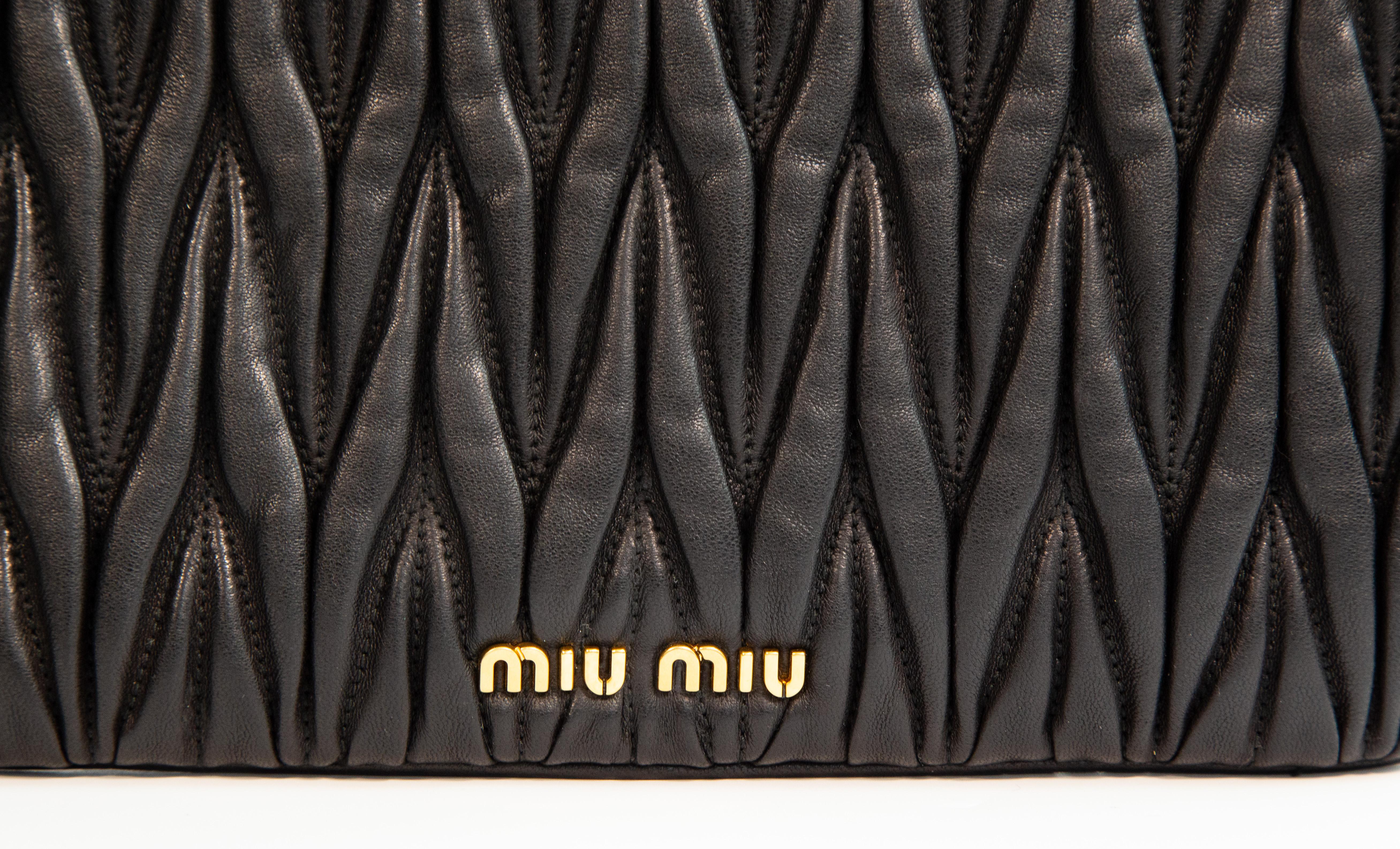 Bolso de mano Miu Miu de piel Matelasse negra y herrajes dorados. El interior está forrado de tela. Consta de un compartimento con un bolsillo lateral deslizante. La bolsa está en muy buen estado, sin apenas signos de uso general.