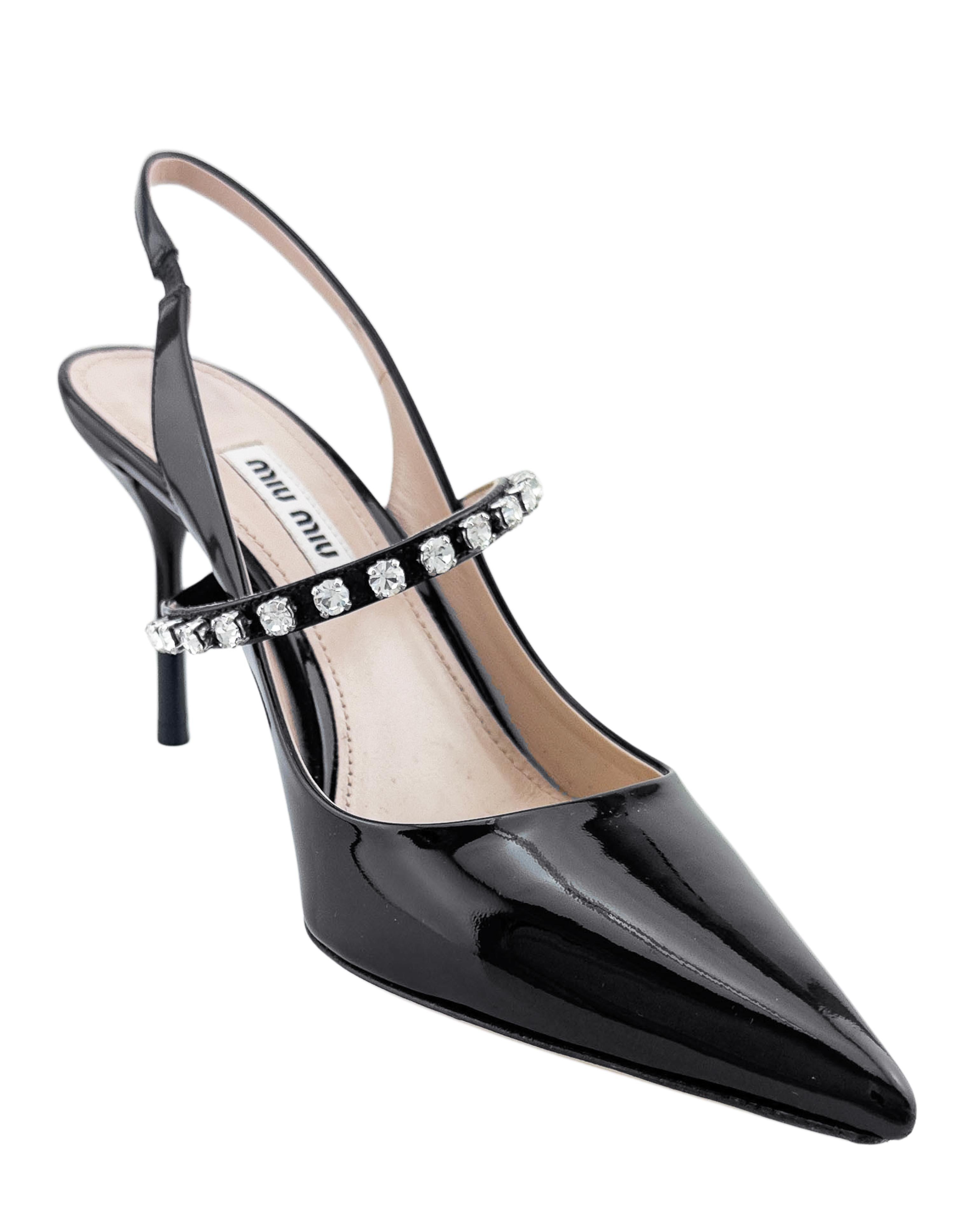 Splendide décolleté Miu Miu in vernice nera degli anni 2000. Un mix perfetto di eleganza e semplicità, con un tocco di brillantezza. Una forma molto classica con un cinturino aggiuntivo al centro del cibo impreziosito da cristalli trasparenti che