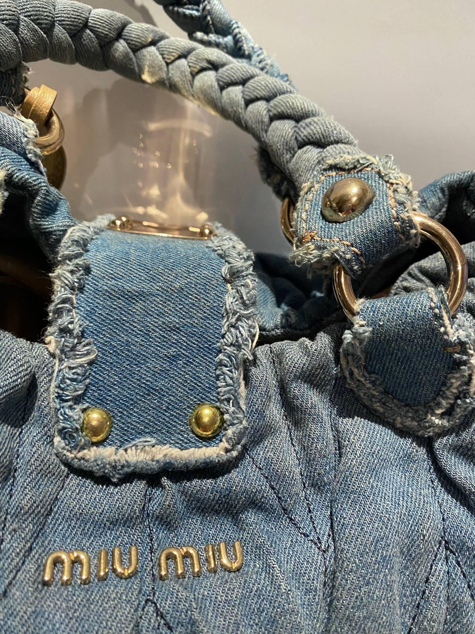 Miu Miu WASHED OUT DENIM MATELASSE BAG

Miu Miu Matelasse bag crafted in blue washed out denim  in signature quilt pattern. Features gold-toned metal hardware and push buckle and braided handles. Interior is lined in purple satin and has a zippered