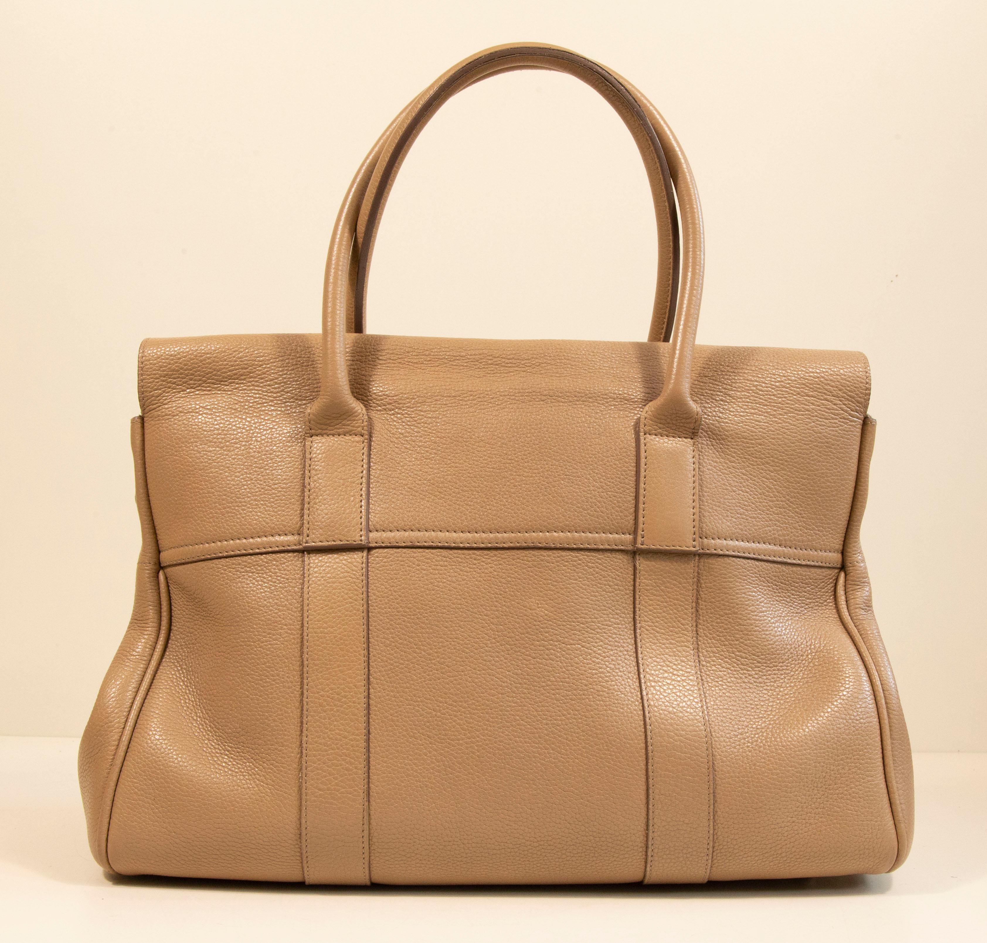 Mulberry Bayswater made of beige grained leather with silver toned hardware. The interior is lined with suede, and next to the major compartment it features three side pockets of which one has a zipper. The bag has hardly any signs of use such as